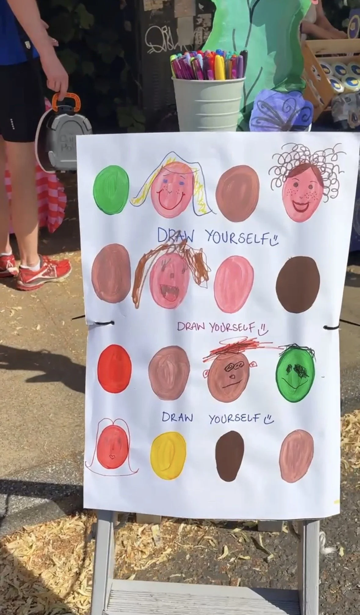 Mounted cardboard with painted face shapes that people have coloured in