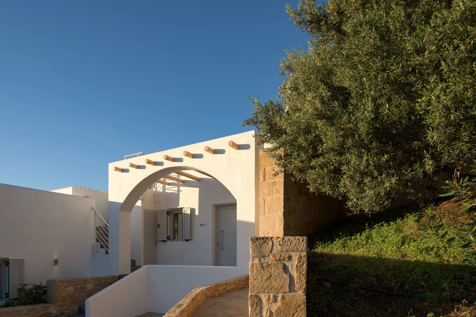 Mediterranean-style suite entrance surrounded by olive trees and natural gardens.
