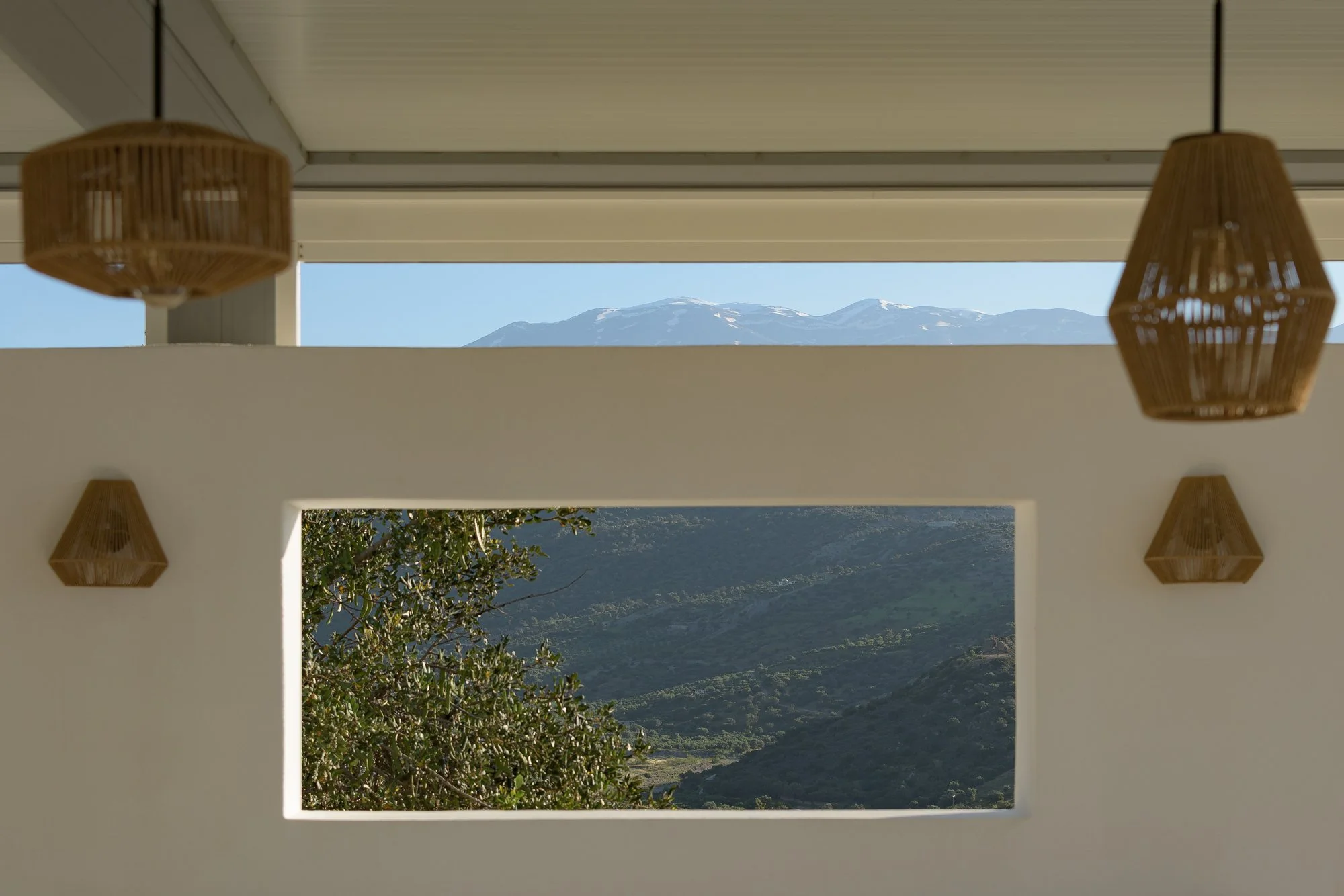 Mediterranean-style interior with woven pendant lights and panoramic South Crete views.