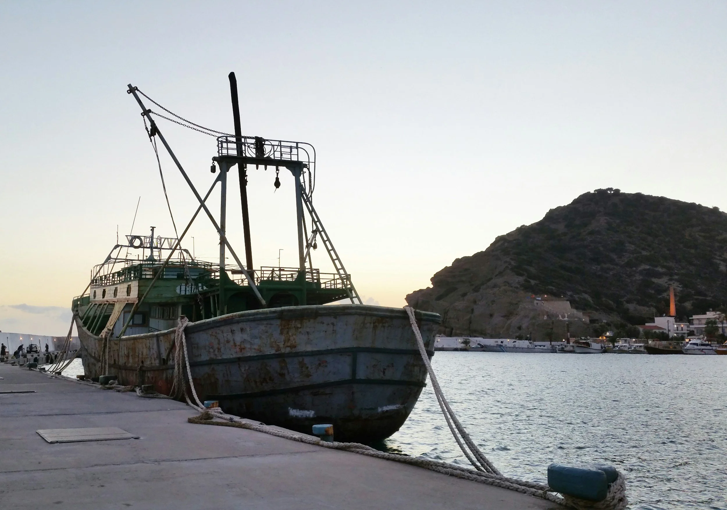 Traditional fishing boat moored in Agia Galini harbour at sunset with the hills of South Crete and the Libyan Sea in the background