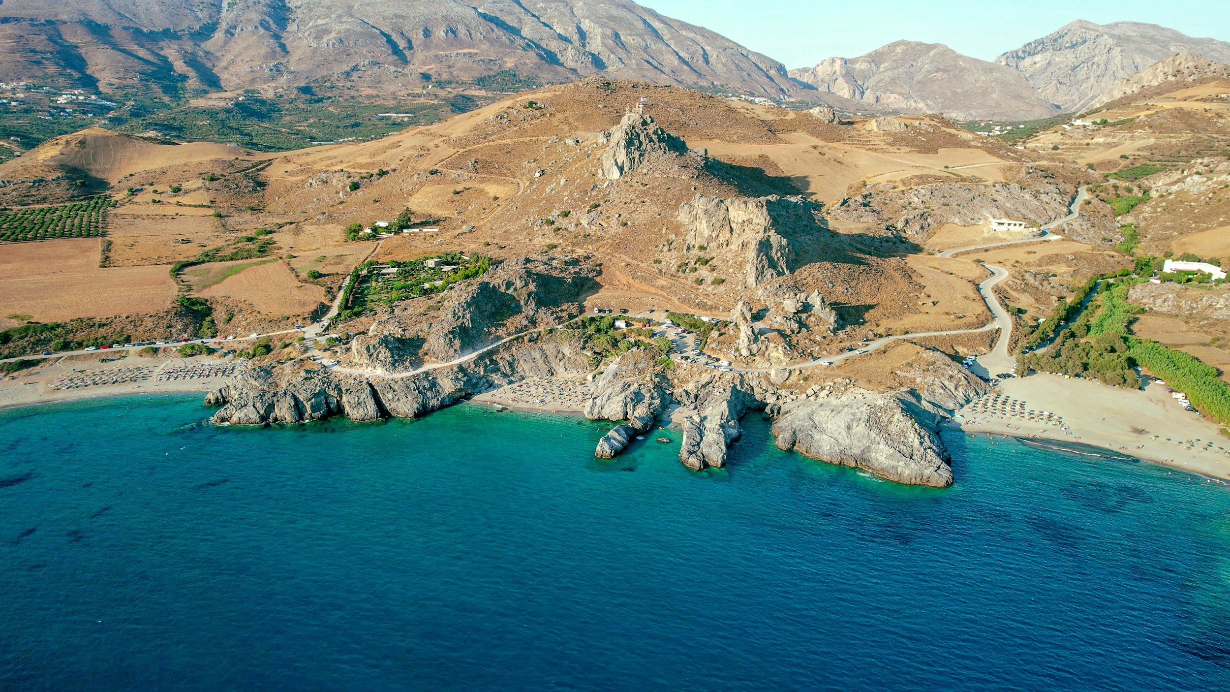 Aerial view of the dramatic Triopetra coastline in South Crete with turquoise sea, rugged mountains and winding coastal roads near Agia Galini