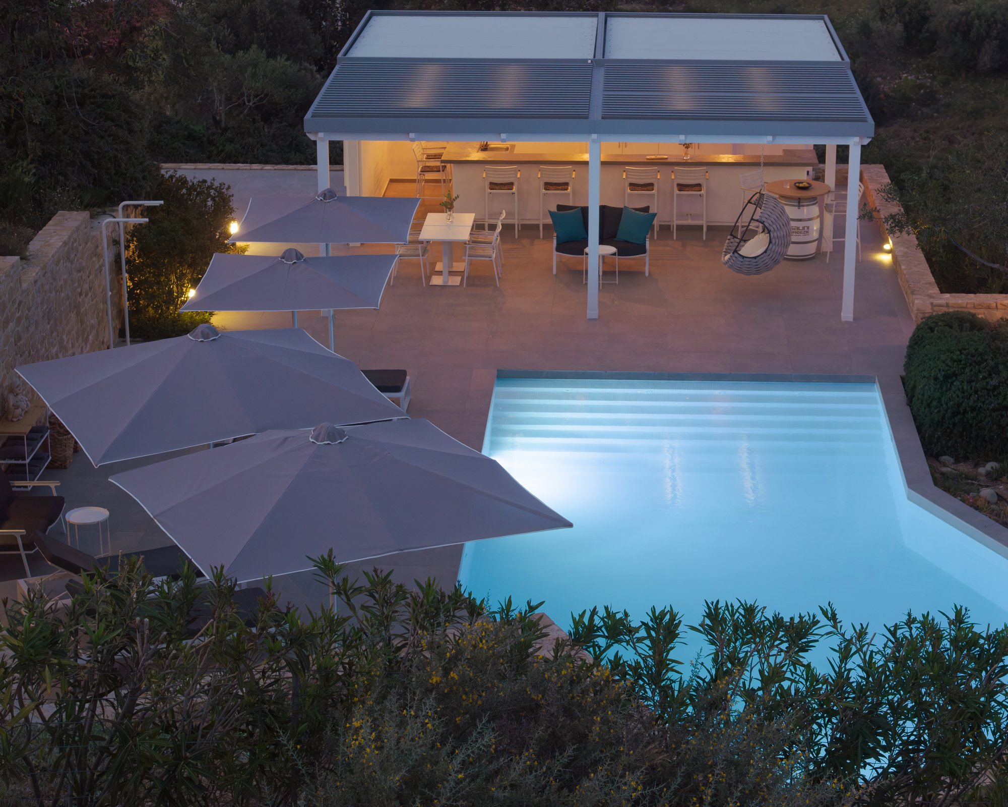 Elevated pool terrace with lounge areas and atmospheric night lighting in Agia Galini.
