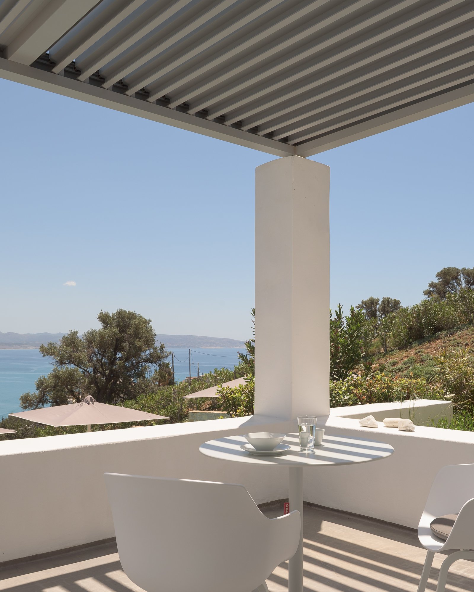 Shaded outdoor dining terrace with minimalist white design in Agia Galini, Crete.