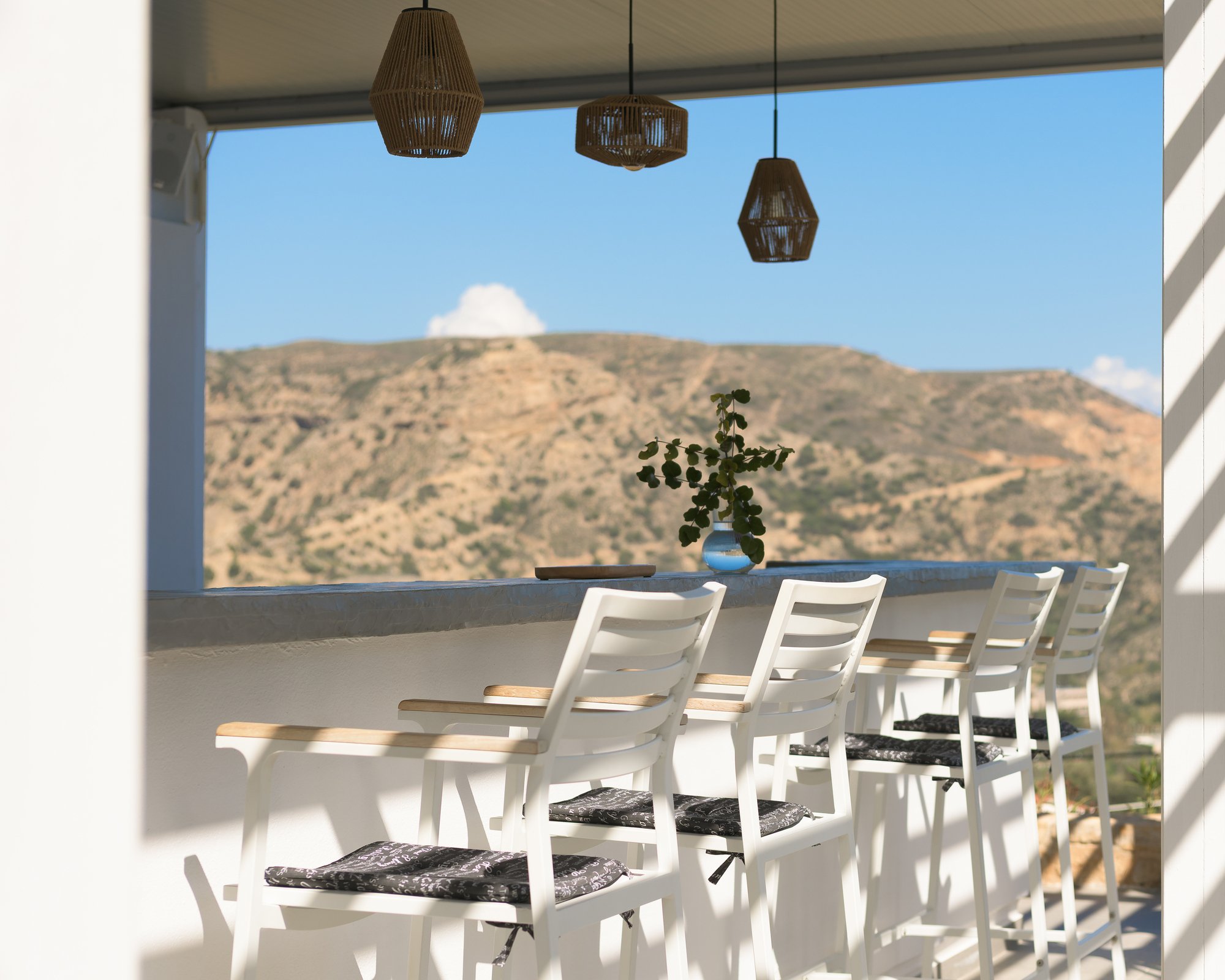 Open-air patio with woven pendant lights and panoramic mountain views at Galini Breeze in South Crete