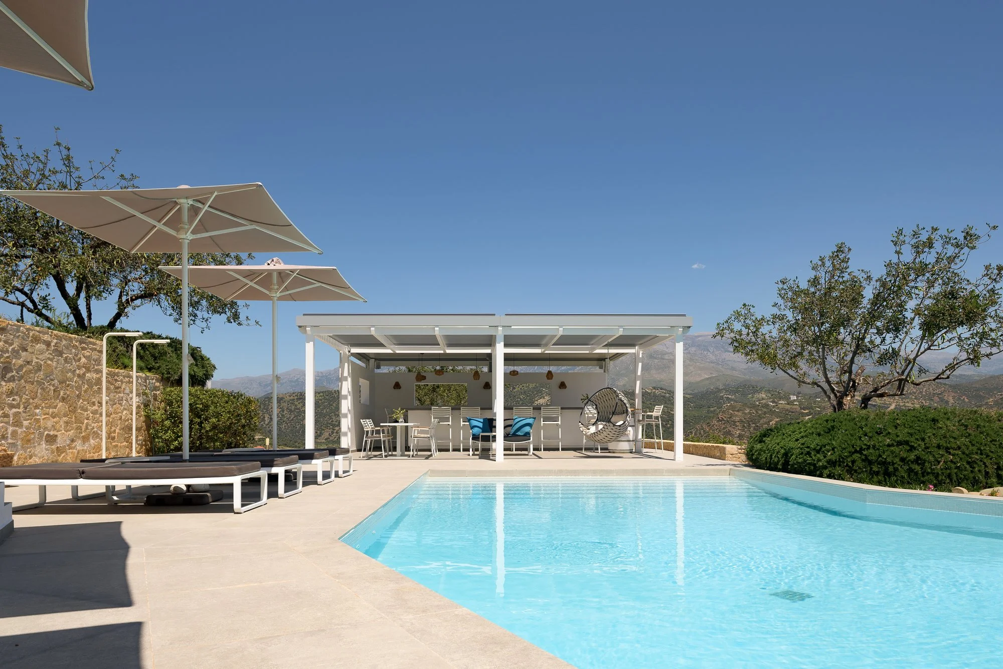 Luxury communal pool area with shaded loungers and hillside views in Crete.