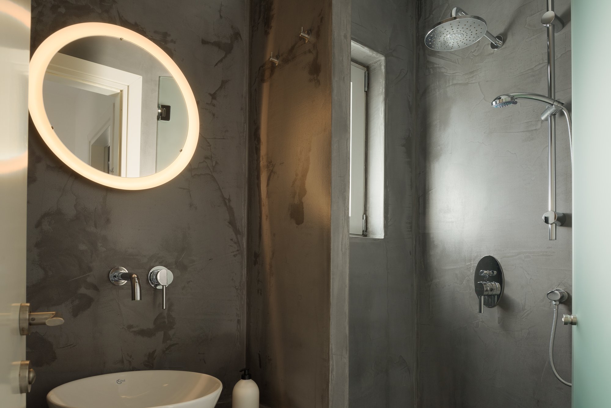 Spa-inspired marble bathroom with illuminated mirror and dark stone textures.