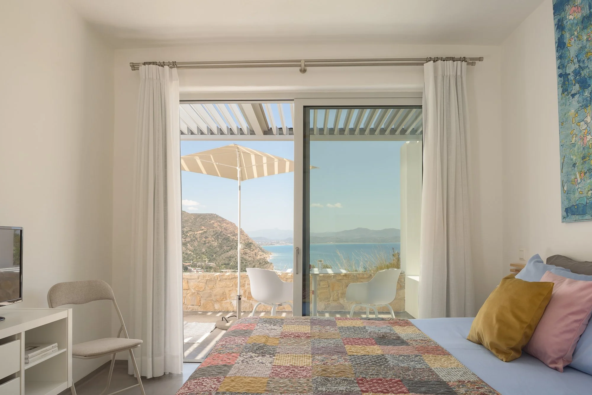 Bright Mediterranean bedroom with panoramic coastal views and natural textures.