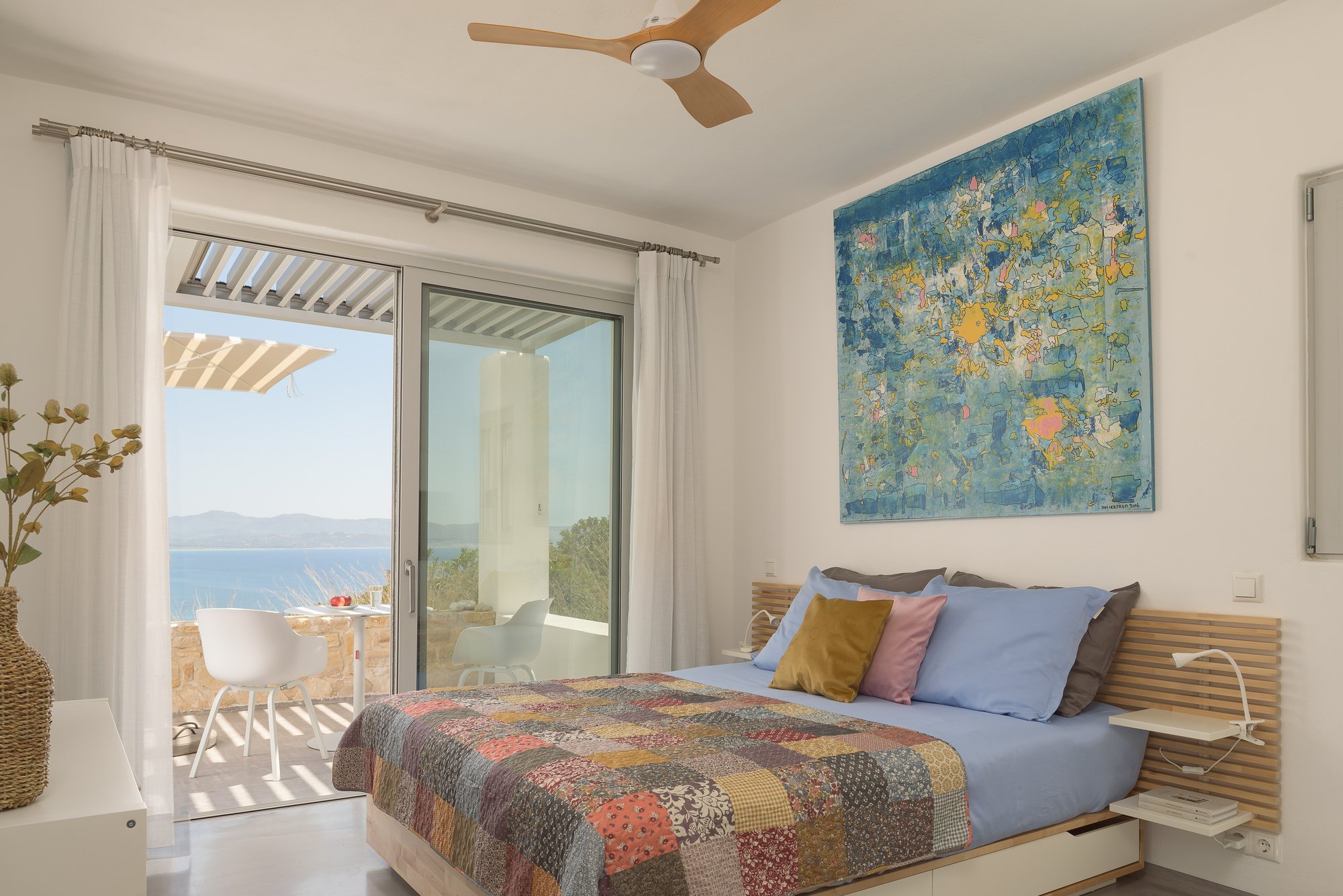 Bright bedroom interior of Studio Sky at Galini Breeze with double bed, colorful artwork, sea-view balcony and natural light in South Crete near Agia Galini