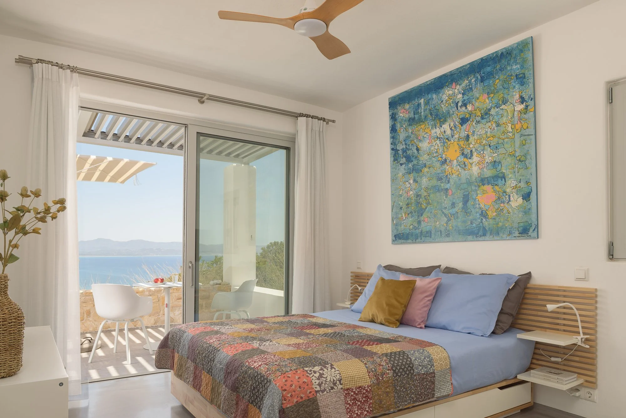 Sea-view bedroom with contemporary art and indoor-outdoor living.