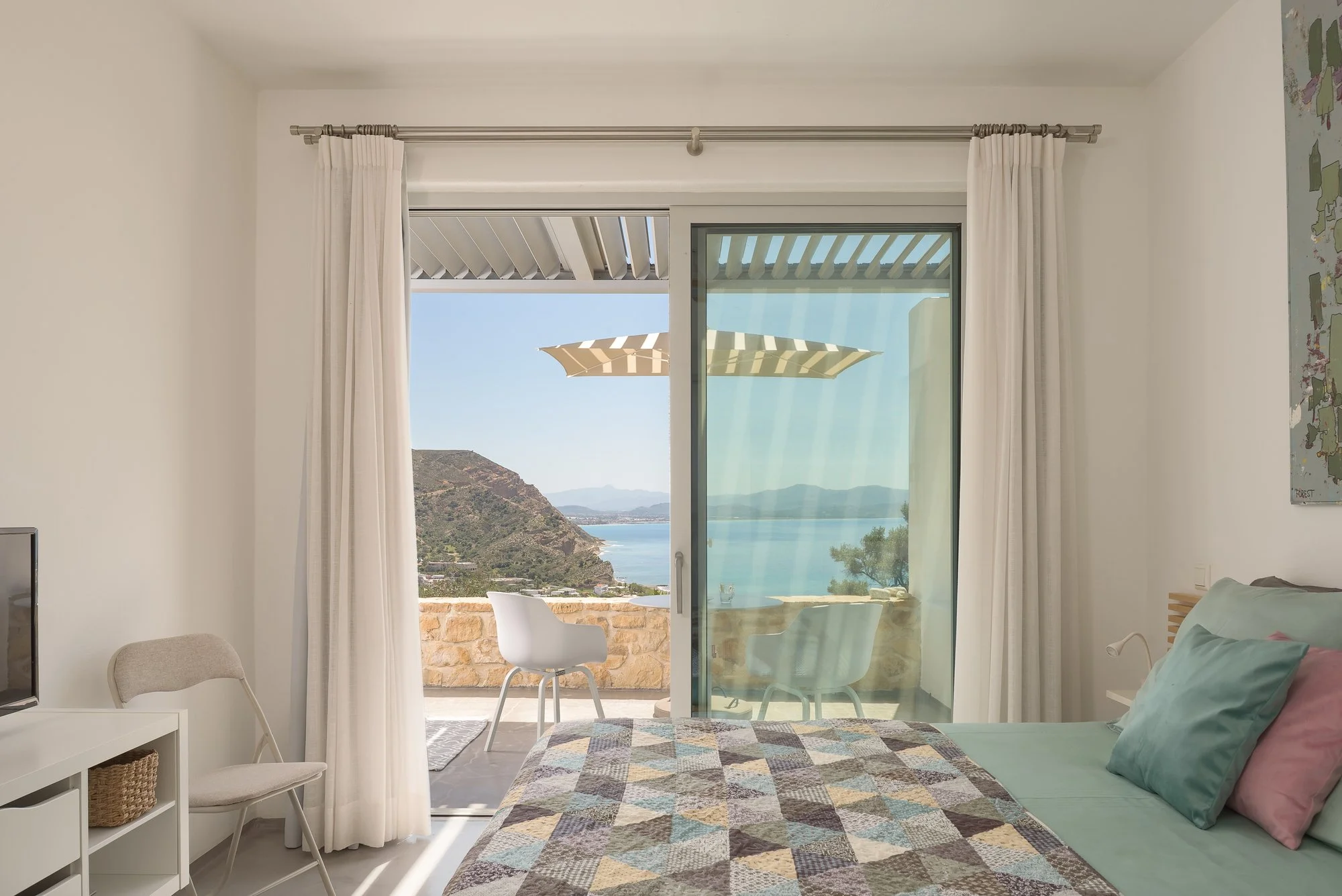 Sea-view boutique bedroom with floor-to-ceiling sliding doors and natural light.