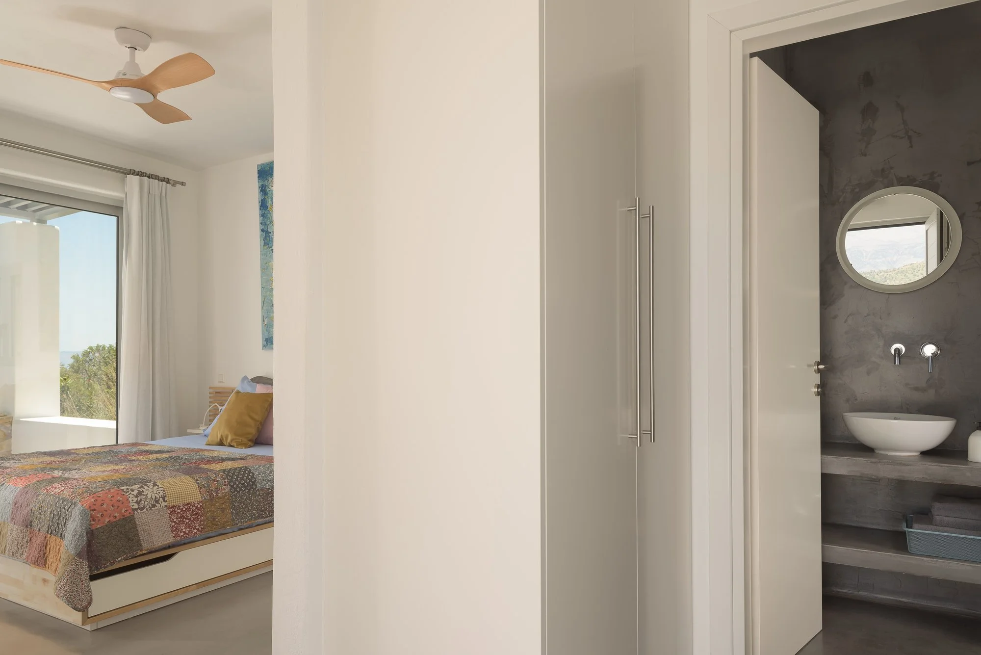 Boutique suite transition between sleeping area and luxury concrete bathroom.