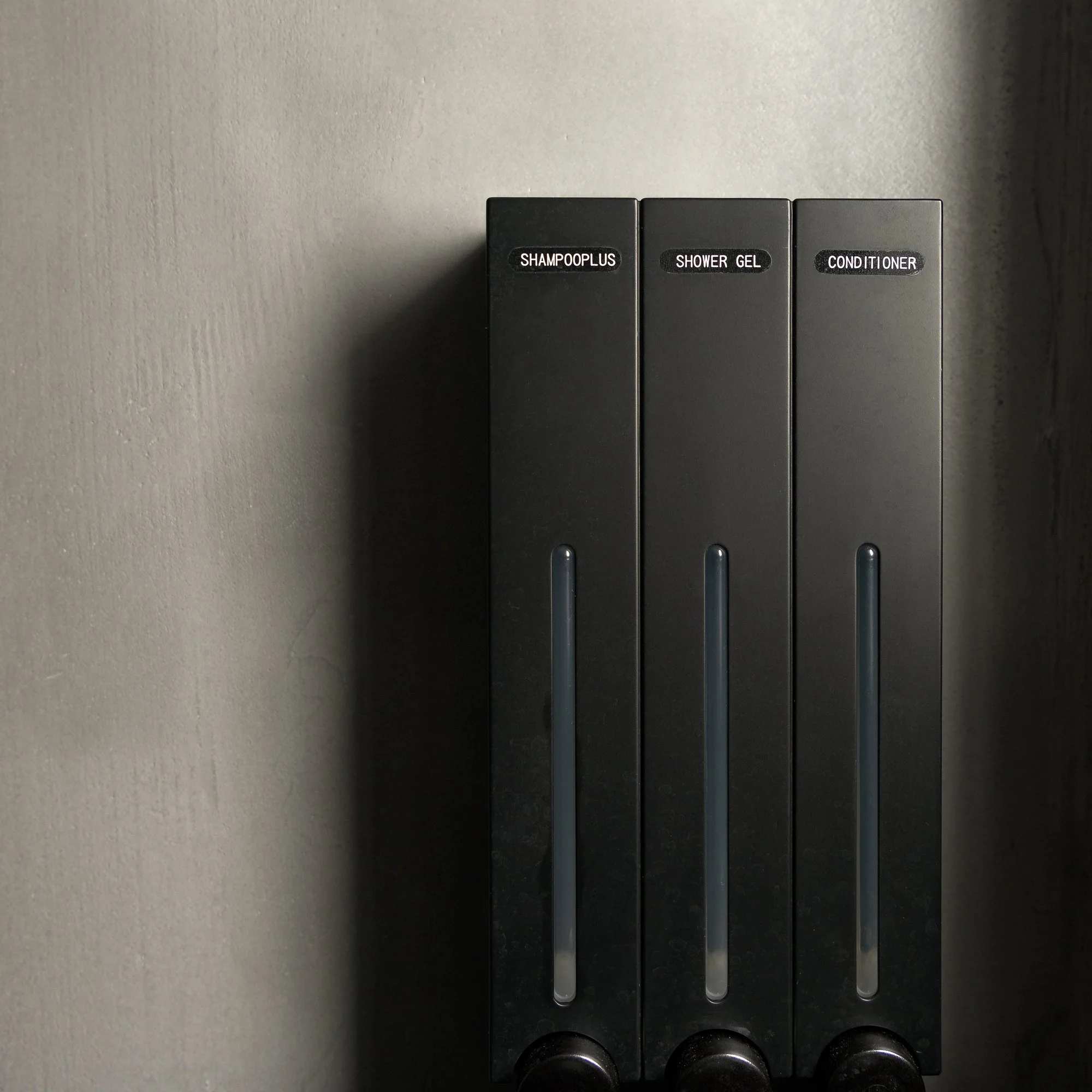 Minimalist shampoo and shower gel dispensers in a modern bathroom at Galini Breeze, reflecting the clean and calm adults-only design aesthetic in South Crete near Agia Galini