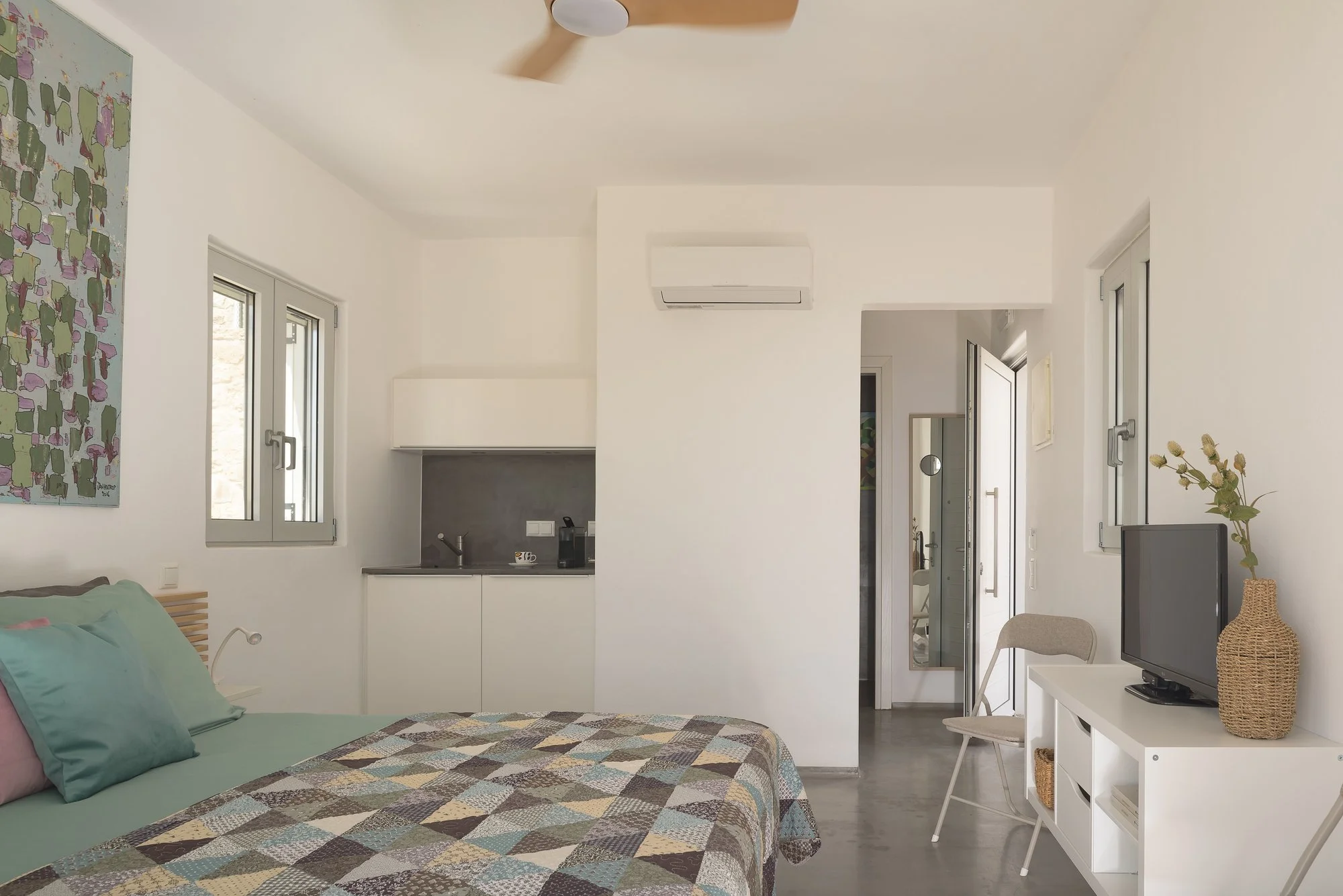 Open-plan boutique accommodation with kitchenette and bright coastal aesthetics.