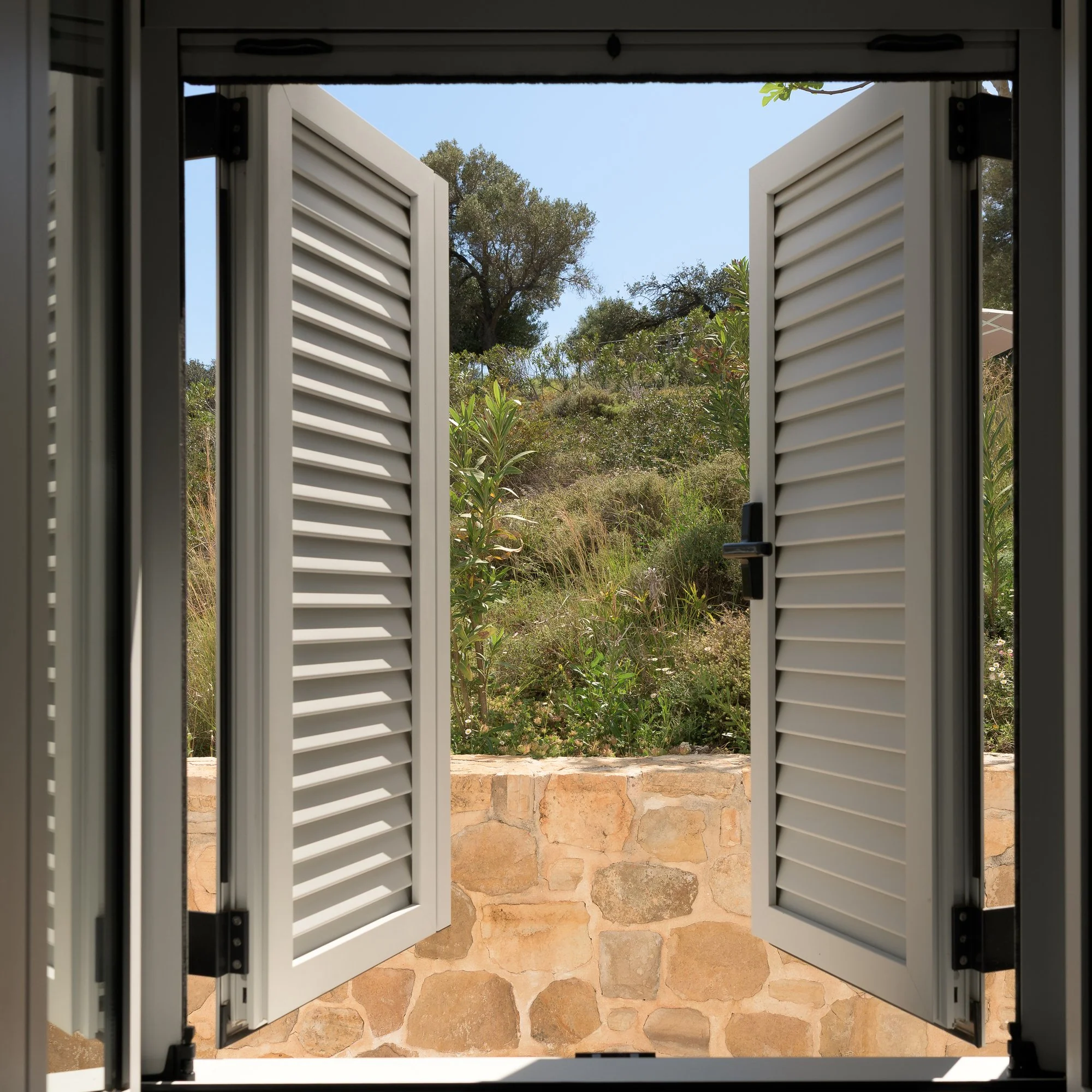 Traditional-style shutters opening onto natural South Crete hillside scenery.