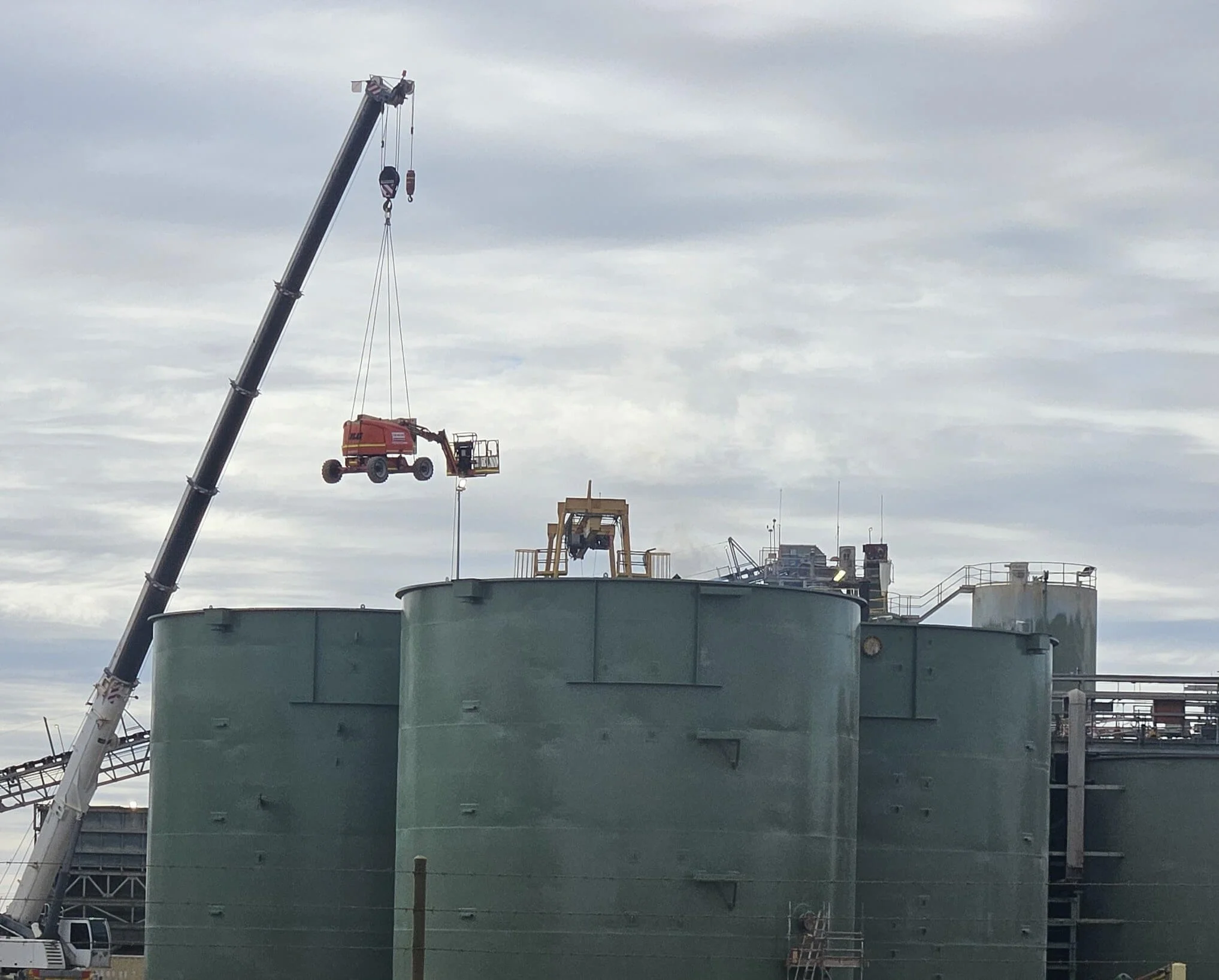 A large ship under construction with a crane lifting equipment or materials onto the vessel at a shipyard.