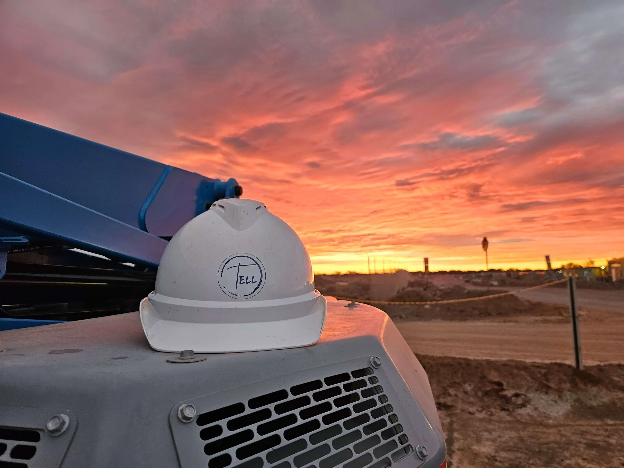 A weather radar or communication device mounted on a vehicle or structure, with a sunset sky of pink and orange colors in the background.