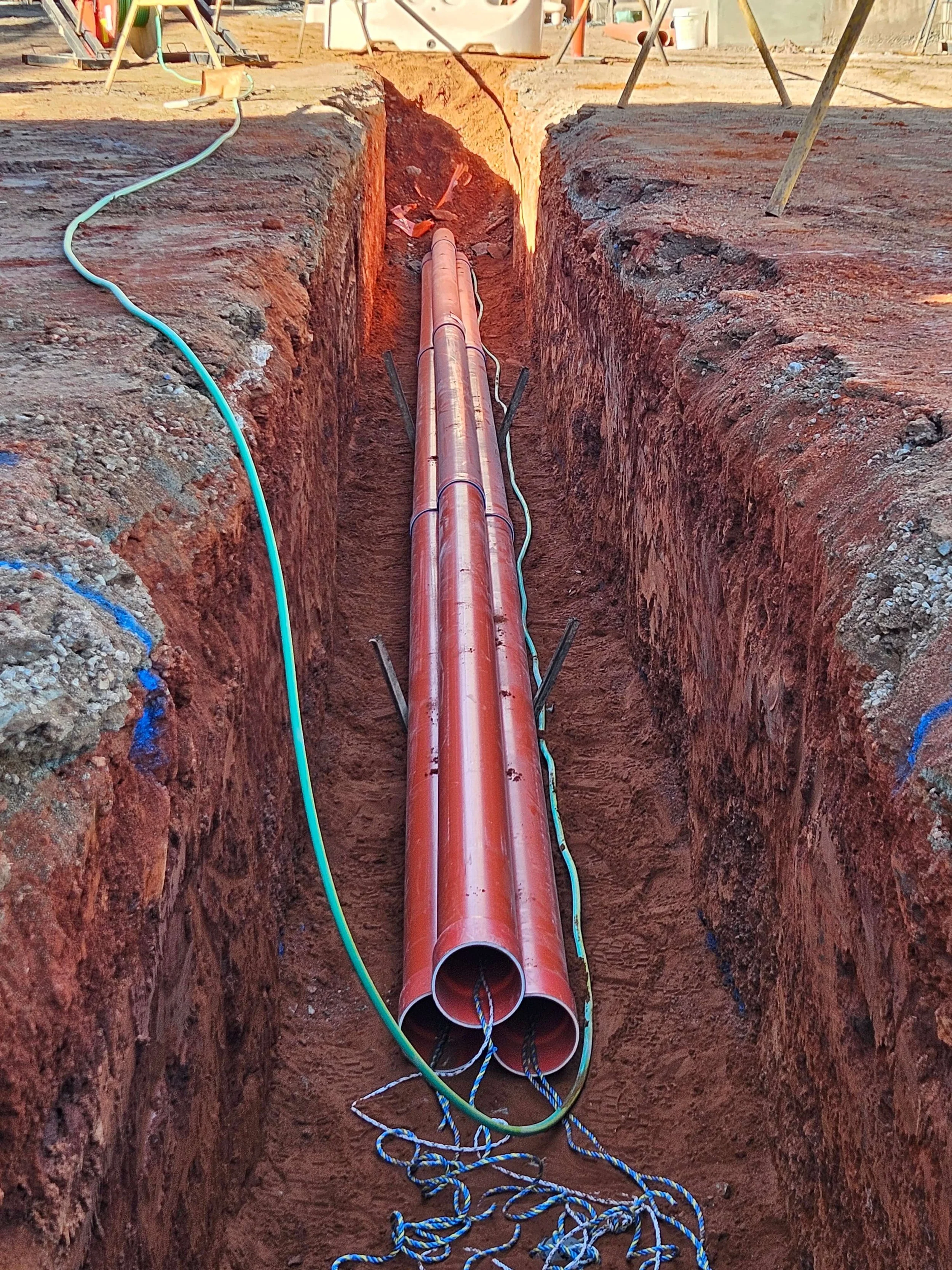 Copper pipes and electrical wiring in a construction trench at a work site.