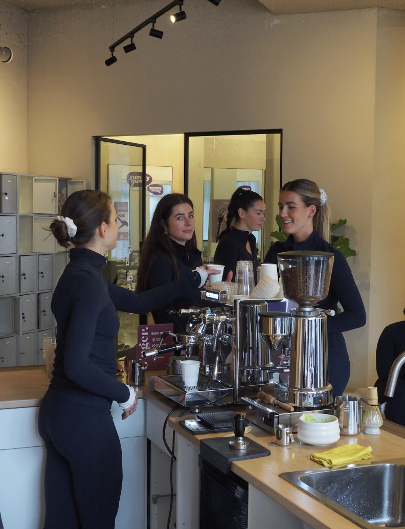 Four women working behind a coffee bar, preparing coffee.