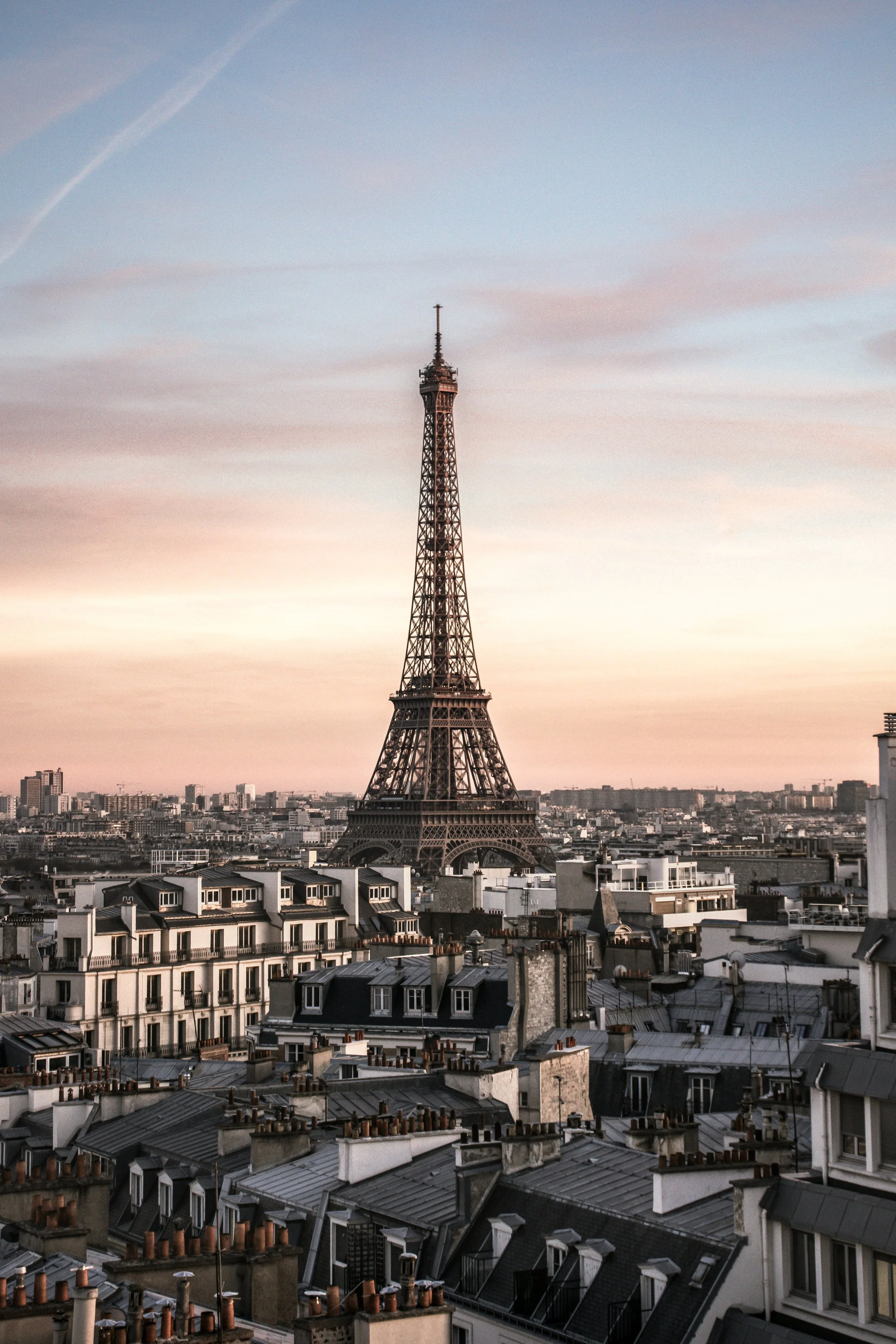 Vue sur la Tour Eiffel de Paris au coucher du soleil, avec des bâtiments résidentiels en premier plan.