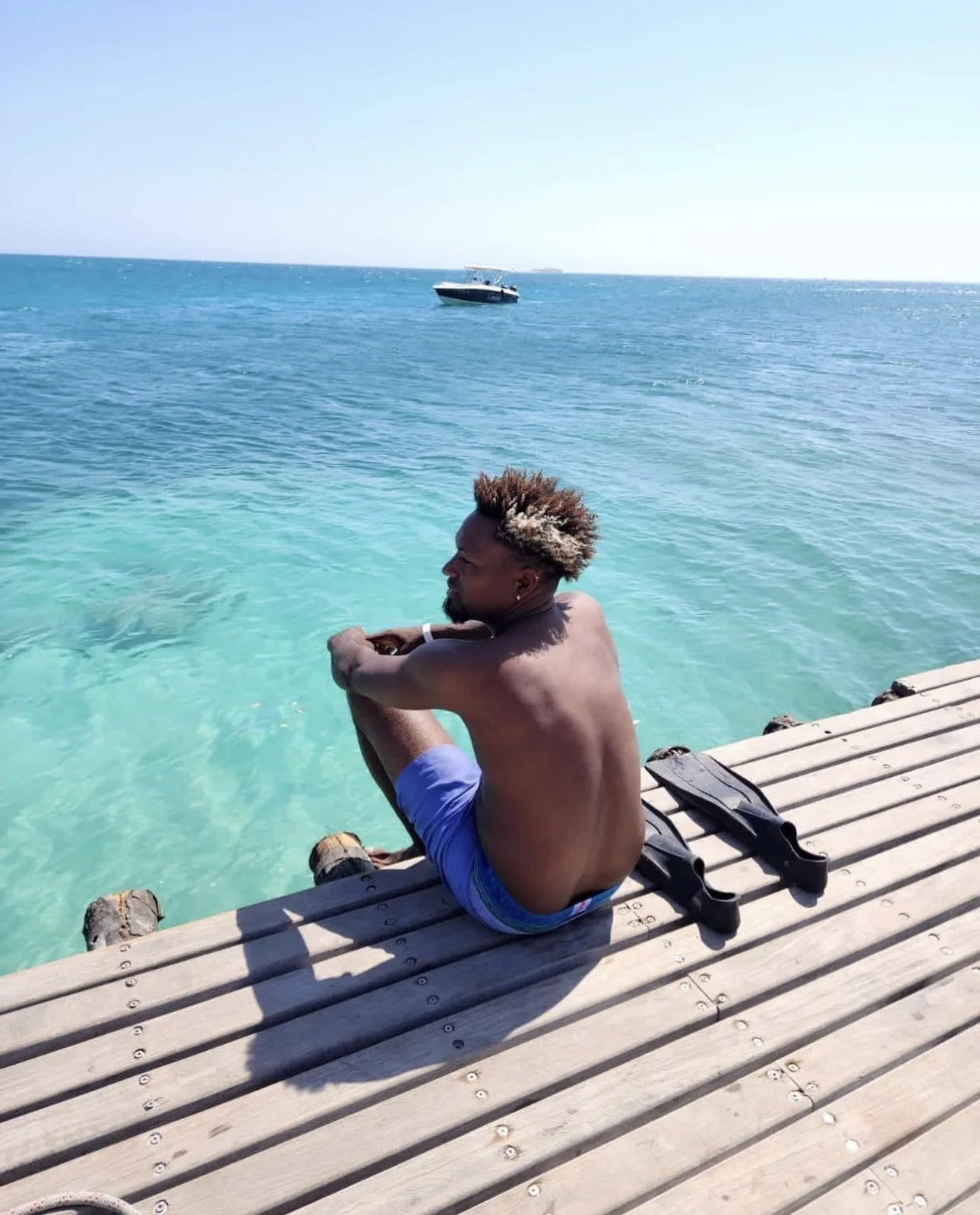 hombre sentado en muelle observando el aguaa cristalina en las islas del rosario cartagena