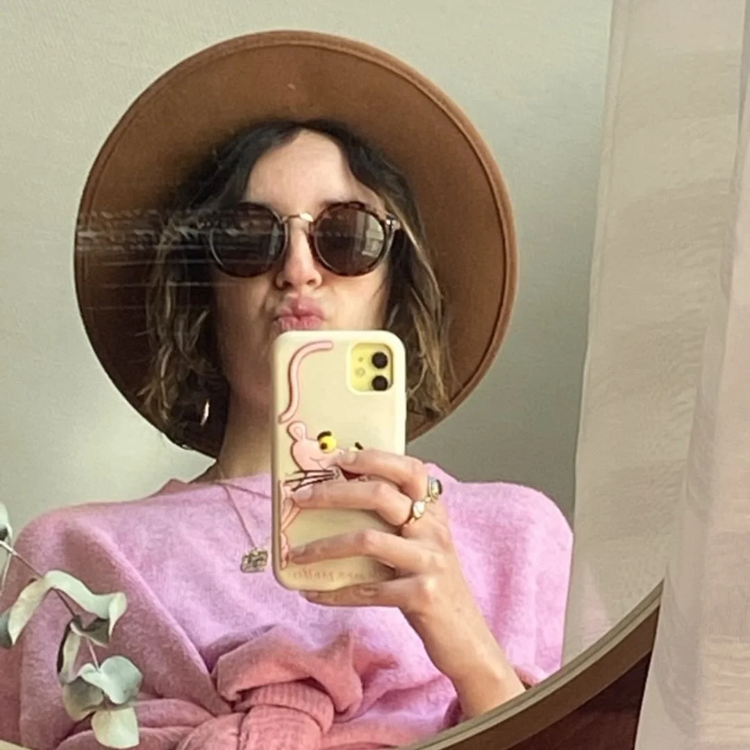 Femme portant un chapeau en paille et des lunettes de soleil, prenant un selfie dans un miroir