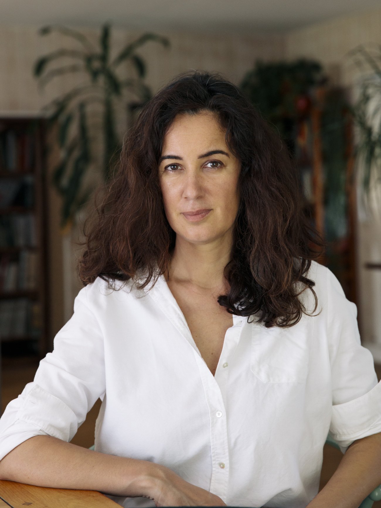 Laure Martin, praticienne narrative, dans son espace de travail entourée de livres et de plantes