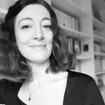 Une femme souriante avec des livres en arrière-plan