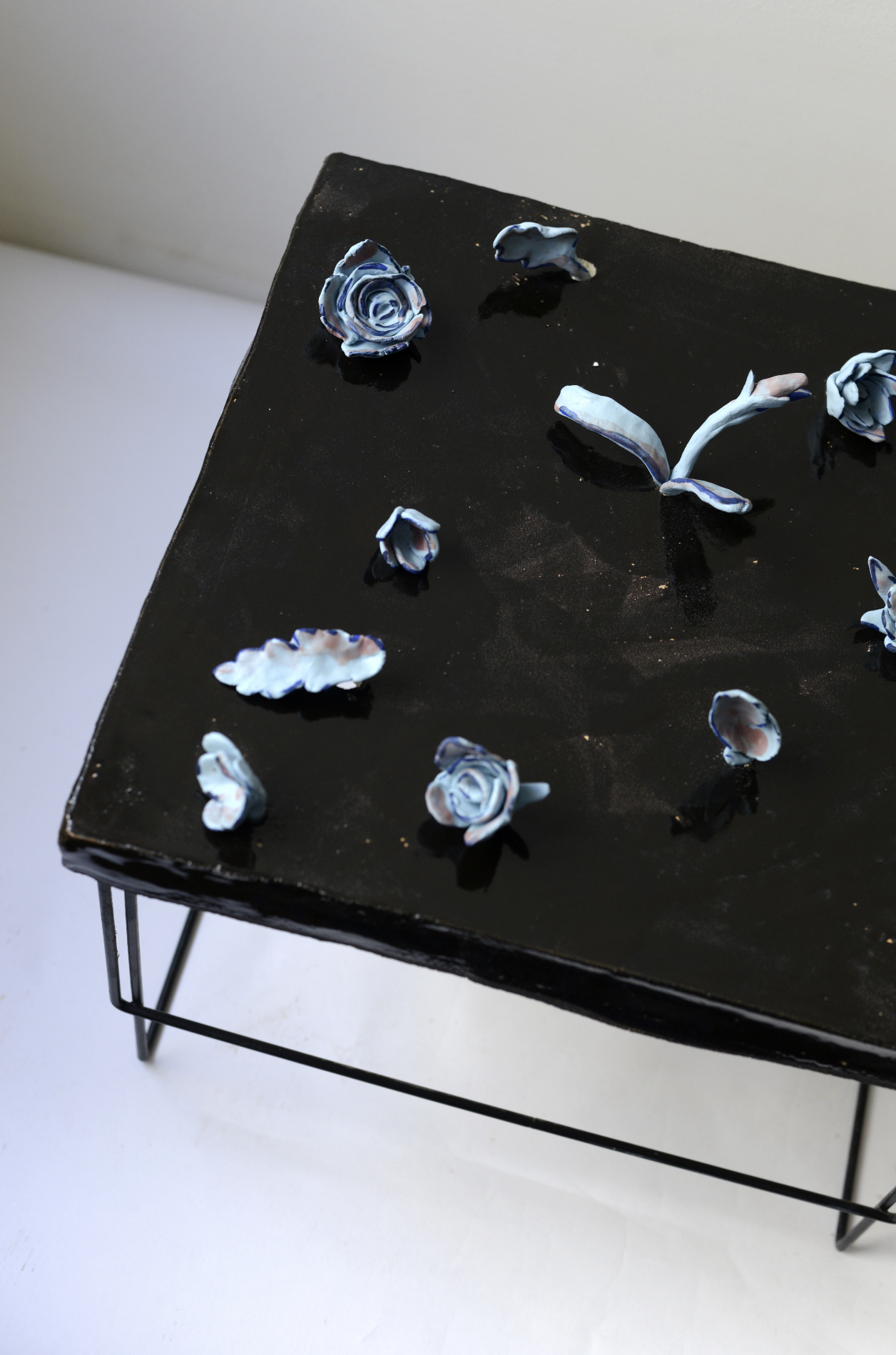 Une table noire avec des décorations en forme de fleurs, principalement en blanc et bleu, disposées dessus.