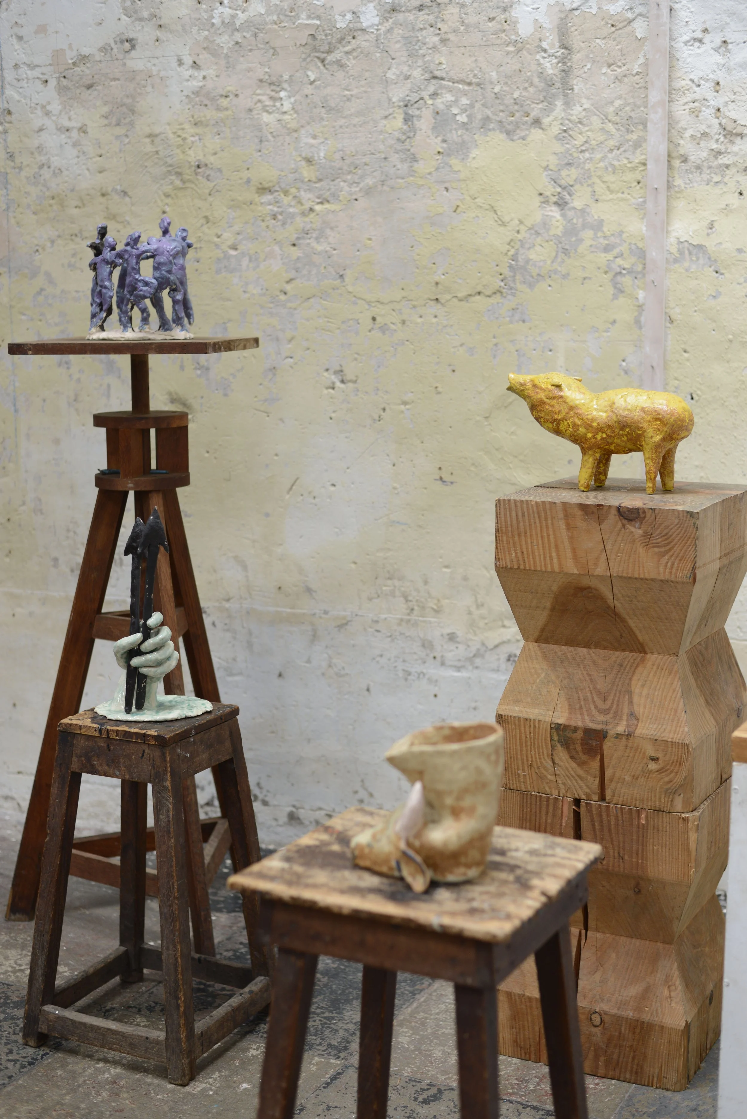 Des sculptures artistiques en céramique et en bois exposées dans un espace d'art ou une galerie, avec un mur en arrière-plan.