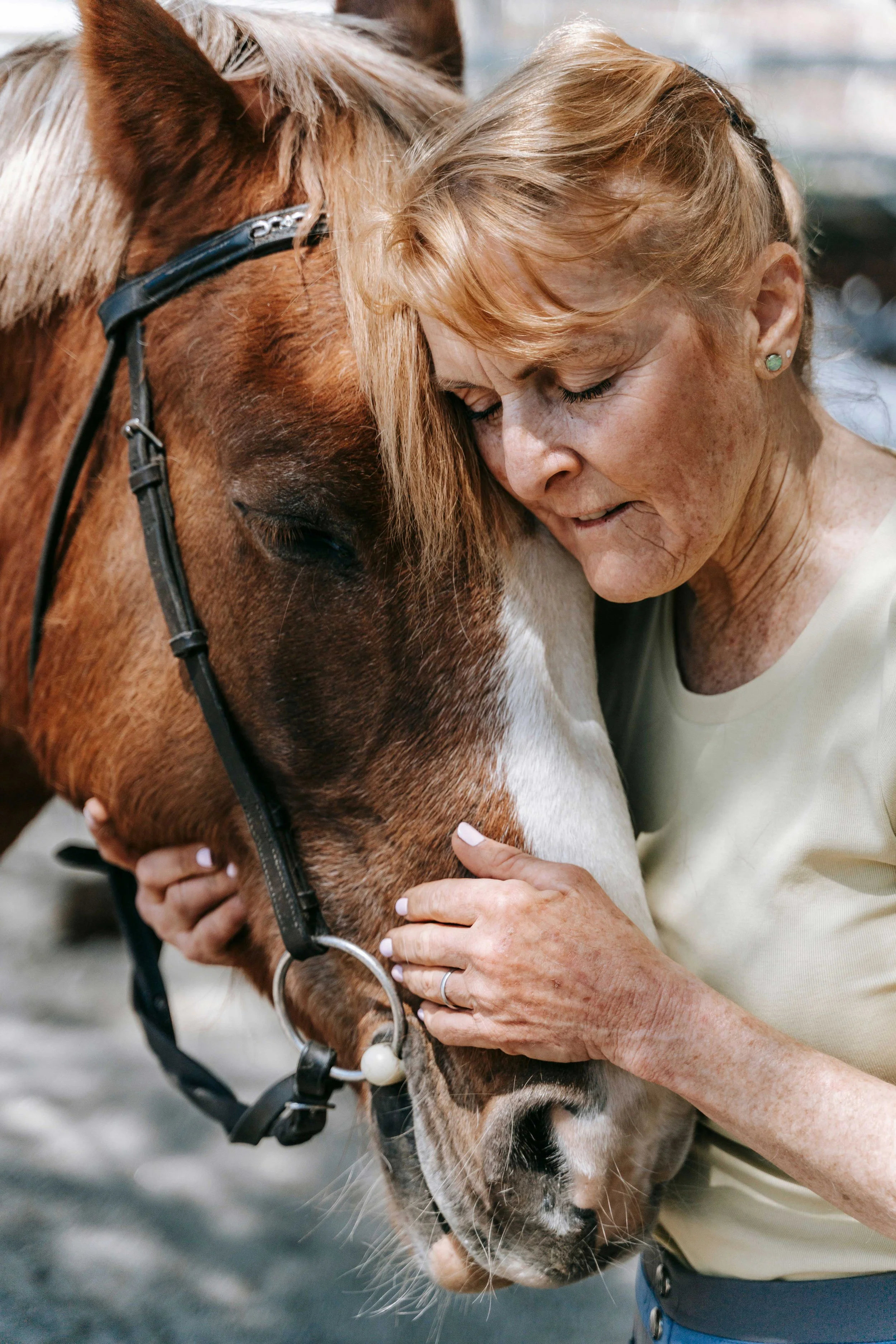 Older woman embracing her horse with eyes closed, highlighting the deep emotional connection between people and animals.