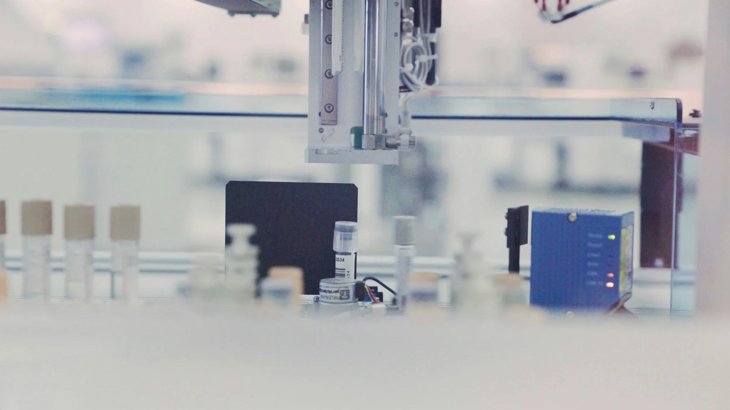 Close-up of laboratory equipment with test tubes and a robotic arm or machine part in a science or medical laboratory.