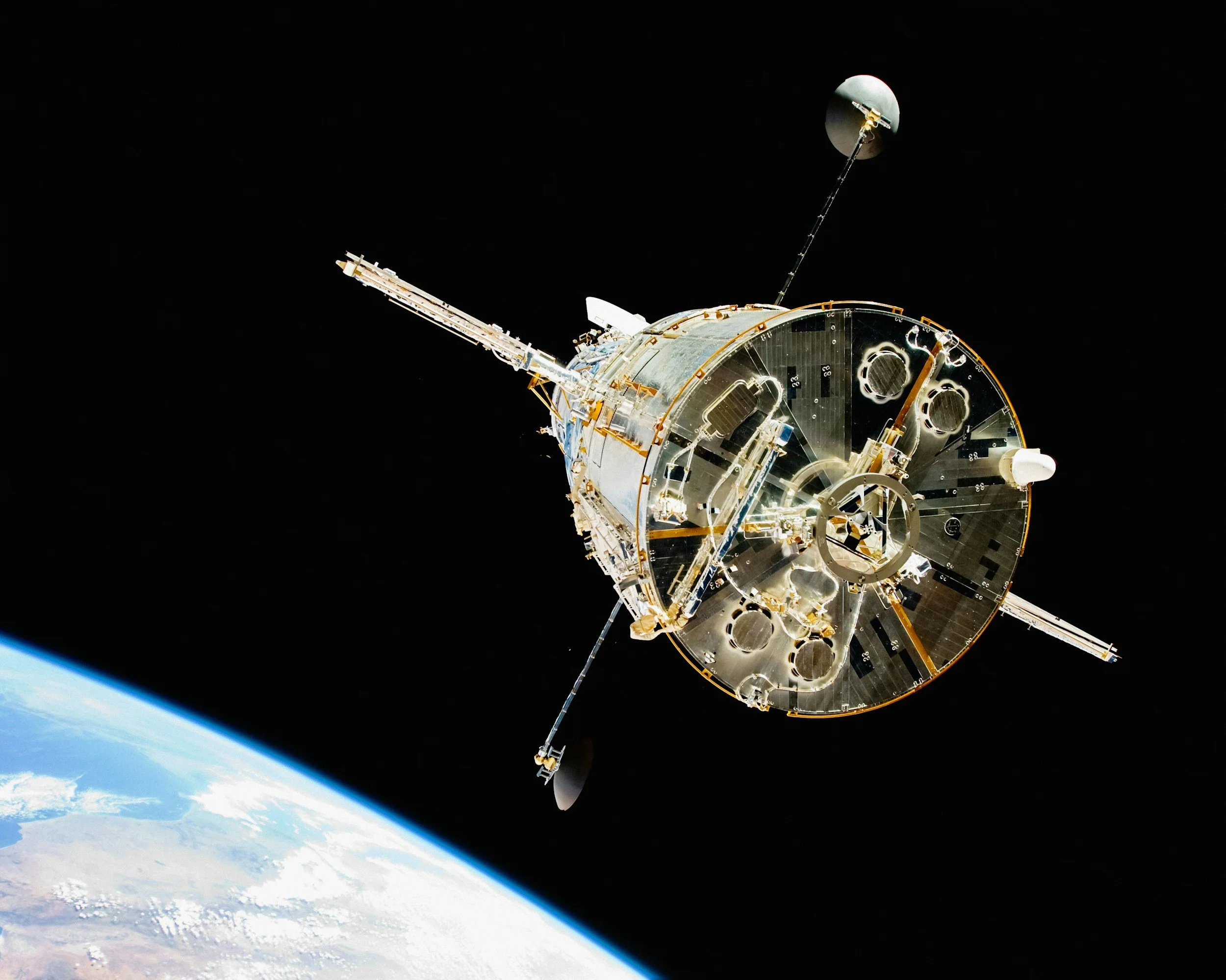 A satellite orbiting Earth in space with part of Earth's atmosphere visible below.