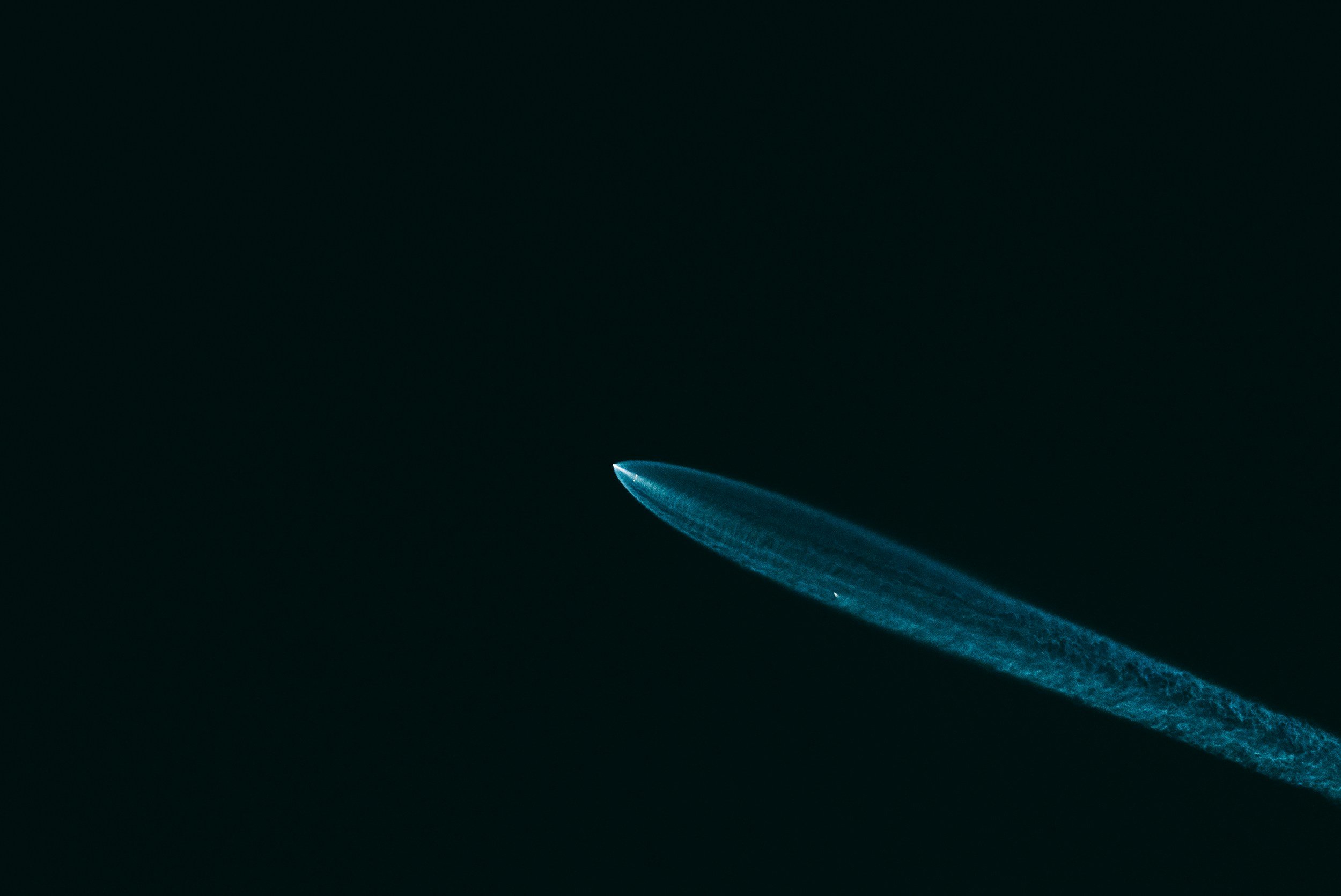 A jet leaving a vapor trail against a dark sky