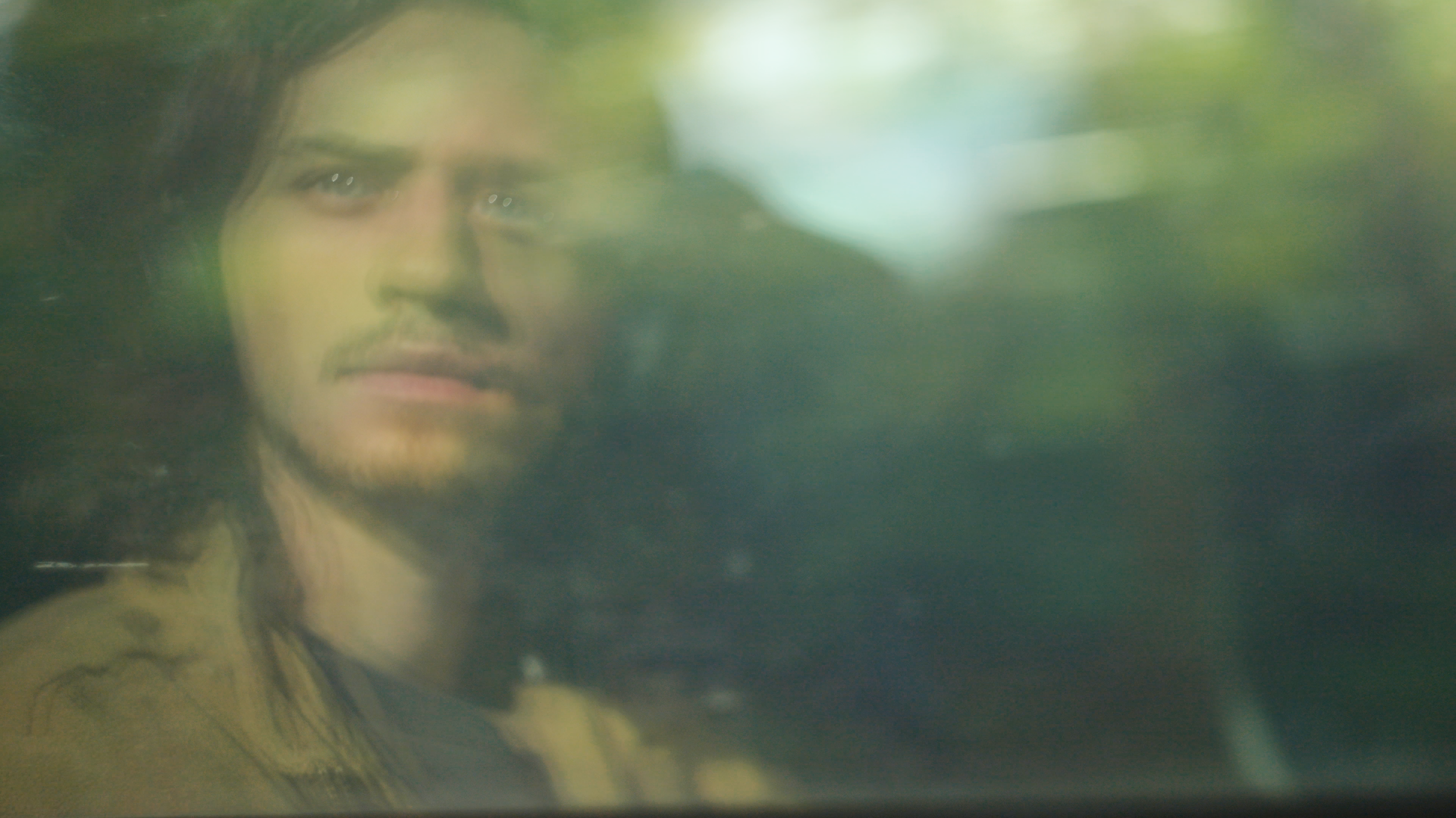 A blurry, green-tinted image of a person's face, looking through a foggy or watery surface.