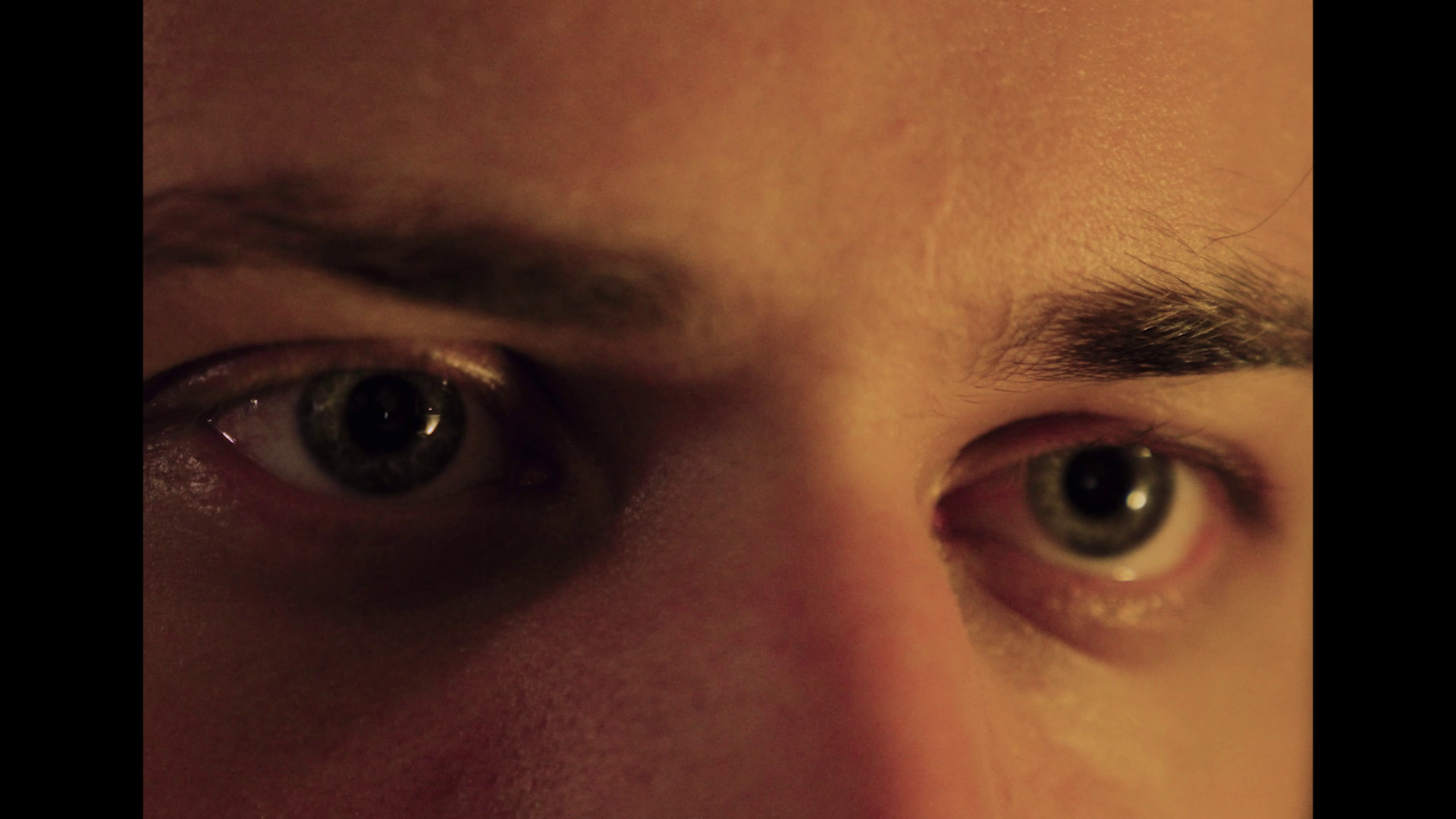 Close-up of a person's face showing their eyes and eyebrows, with one eye partially closed.