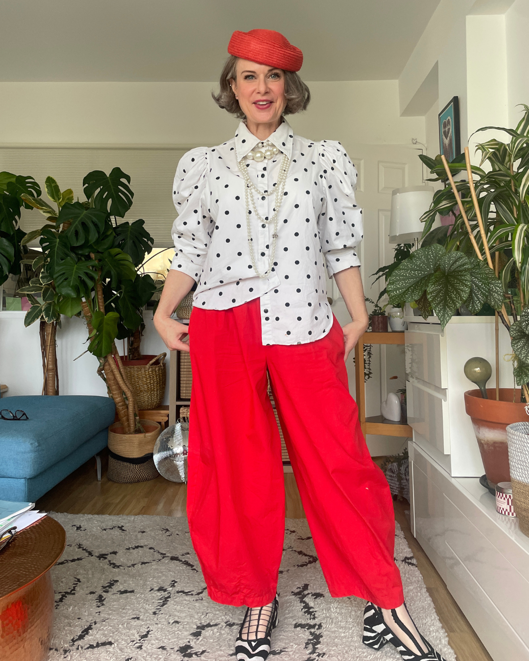 Base layer only: white polka dot shirt with pearls that get lost against the white, red beret and red wide-leg trousers.