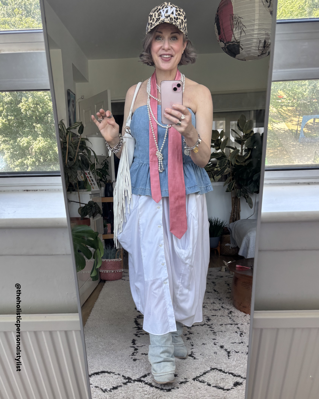 Maximalist summer outfit over 40 — denim peplum tube top, white maxi shirt skirt, pink tie, leopard cap, fringe bag, pearl necklace — creative style over 40