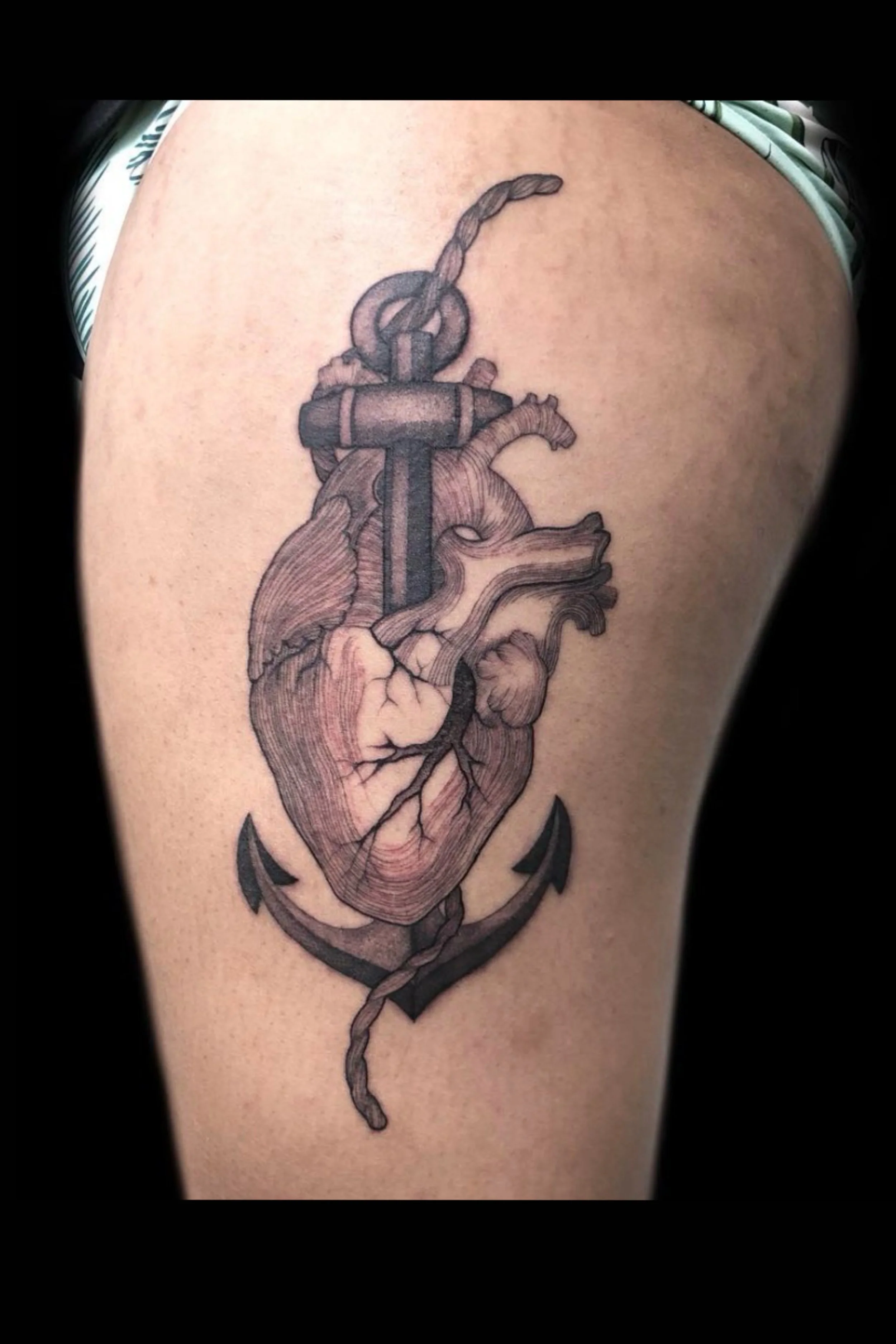 heart and anchor illustrated style tattoo in black and grey on the leg