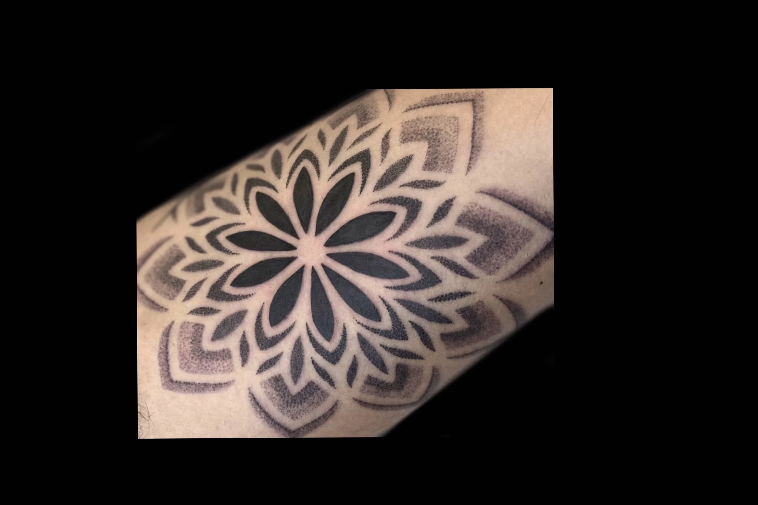 Close-up of a tattoo featuring a symmetrical, intricate mandala design by Marie Makowski