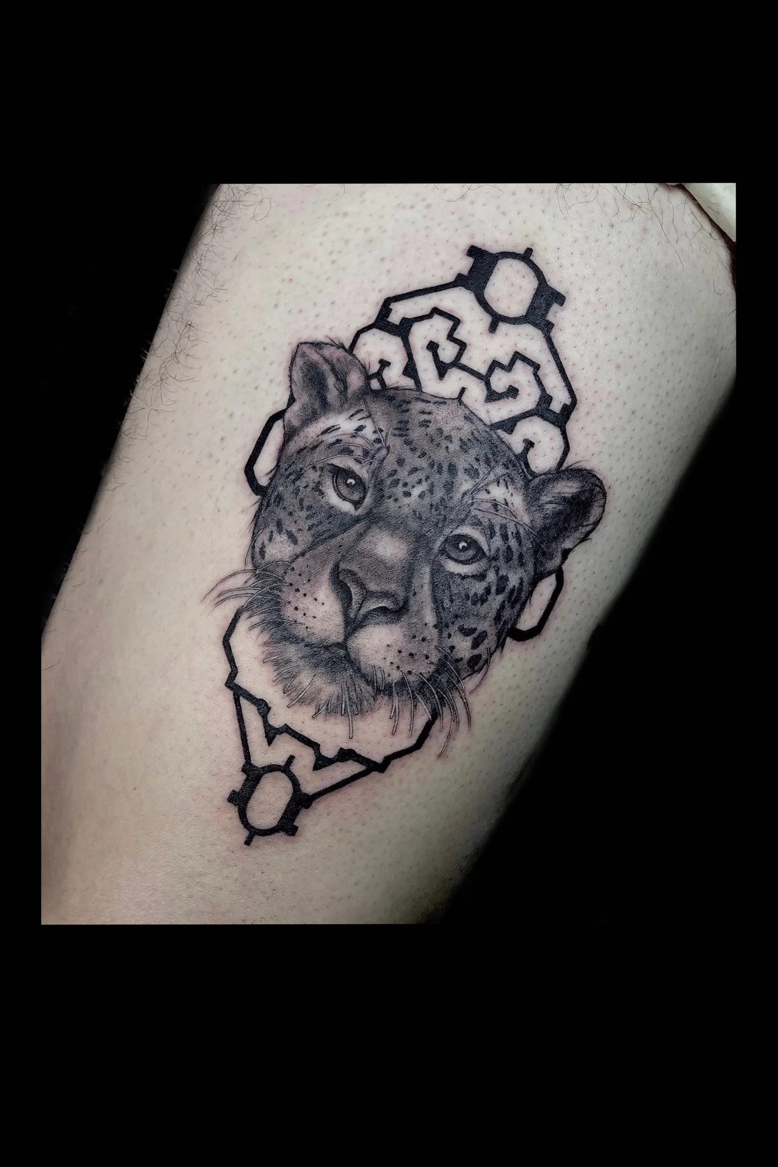 A tattoo of a leopard's face with a geometric patterns by Marie Makowski