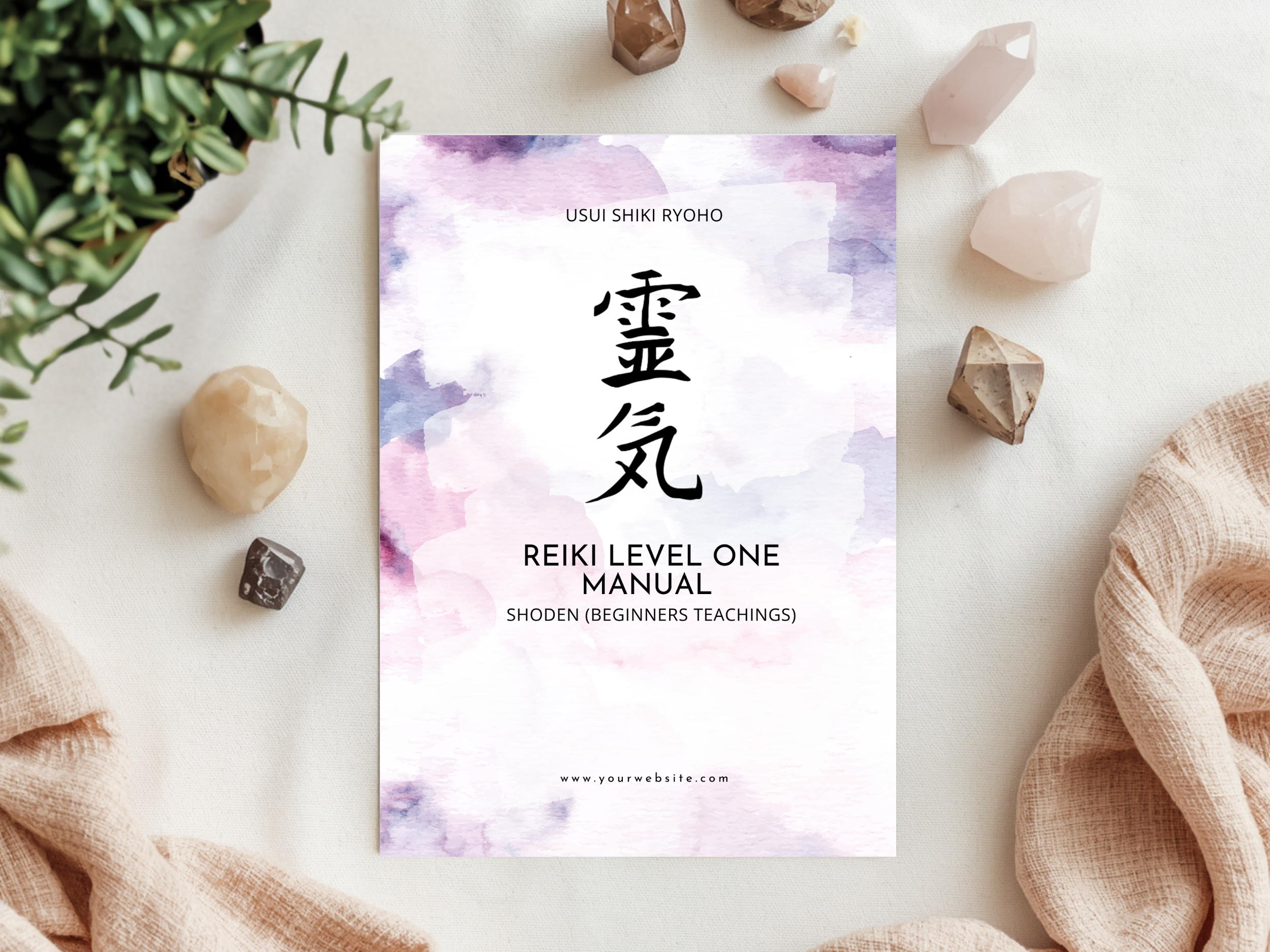 A Reiki manual titled 'Usui Shiki Ryoho' with Japanese characters, watercolor background, surrounded by crystals, a small plant, and soft fabric on a white surface.