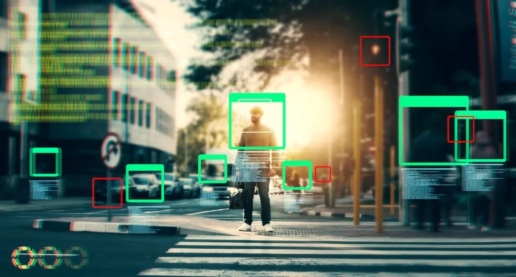 A person with a backpack standing at a crosswalk in an urban city street, with digital overlays including face recognition boxes and data streams, during sunset.