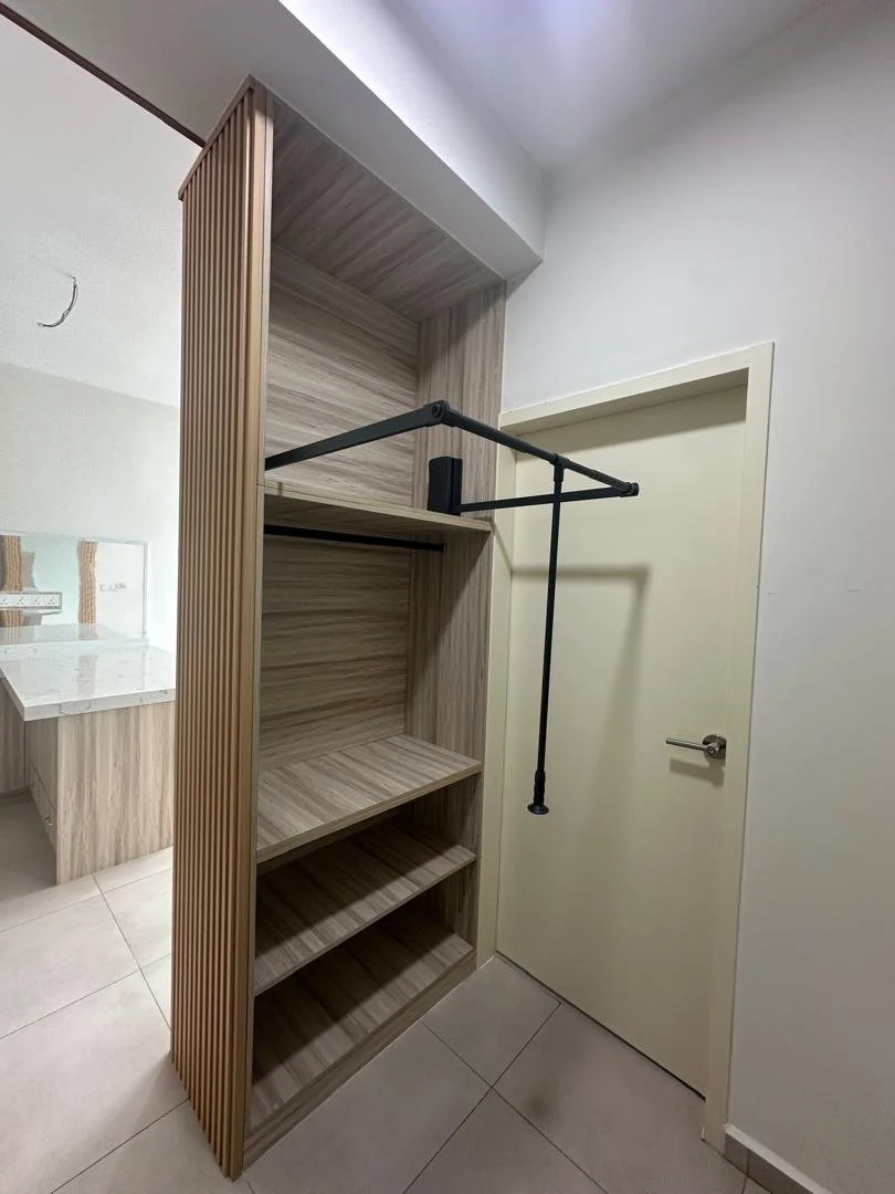 Open wooden closet with horizontal shelves, a hanging bar, and a sliding barn door in a room with tiled floor and white walls.