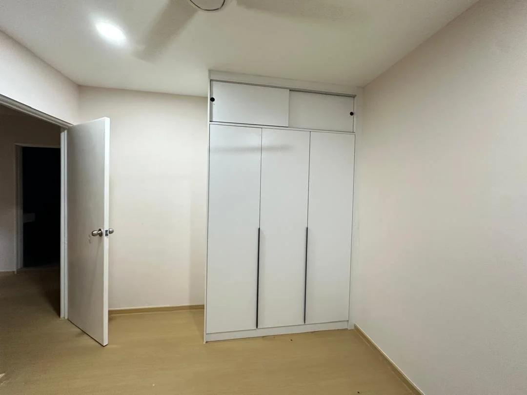 Empty room with white walls, light wooden flooring, a white door, and a closed wardrobe with sliding doors.