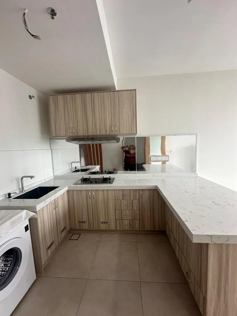 Kitchen with wooden cabinets, a white marble countertop, a sink, gas stove, mirror, and washing machine.