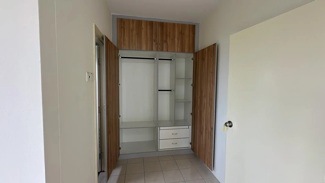 Empty closet with wooden doors and shelves, in a room with tiled floor and plain walls.