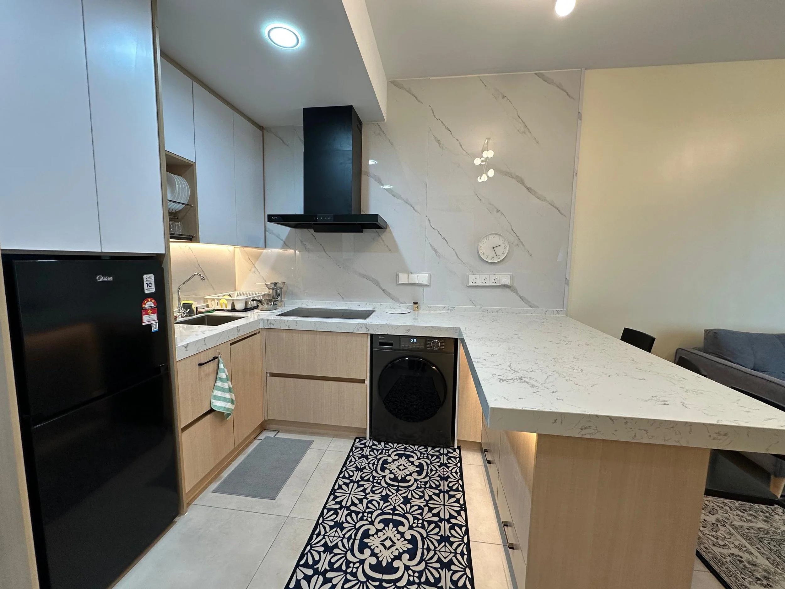 Modern kitchen with white marble backsplash, black range hood, wooden cabinets, and a black refrigerator.