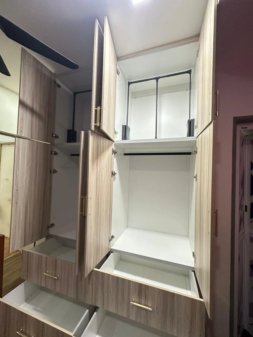 Open empty light wood-colored wardrobe with multiple compartments, drawers, and hanging rods.