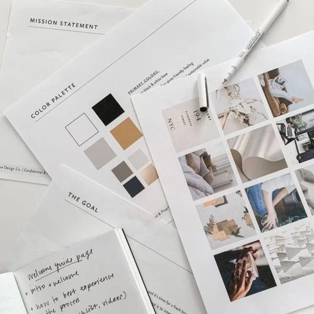 A collection of printed sheets, including a mission statement, a color palette with black, beige, gray, and white swatches, and a mood board with photos of interior design elements and a hand holding a camera, along with pens on a white surface.