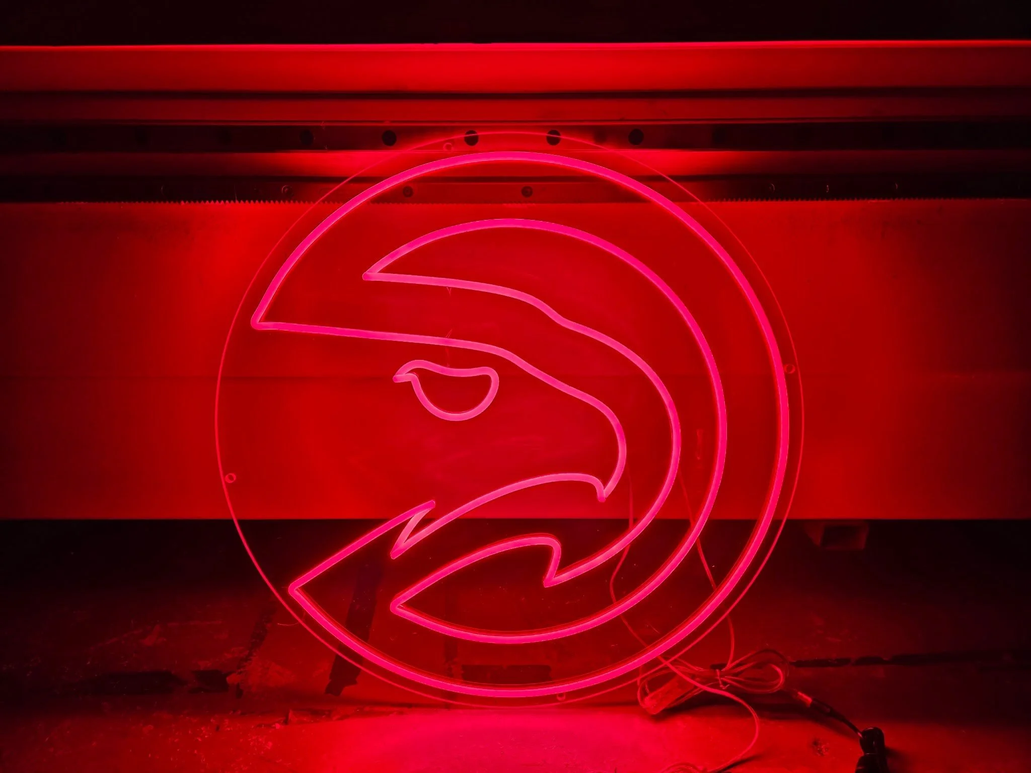 Bright pink neon sign of a flamingo on a red background.